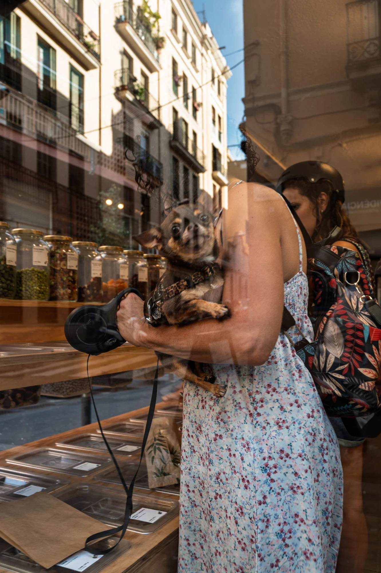 Woman holding a chihuahua reflected in a shop window, street photography in Barcelona — Leica Q3