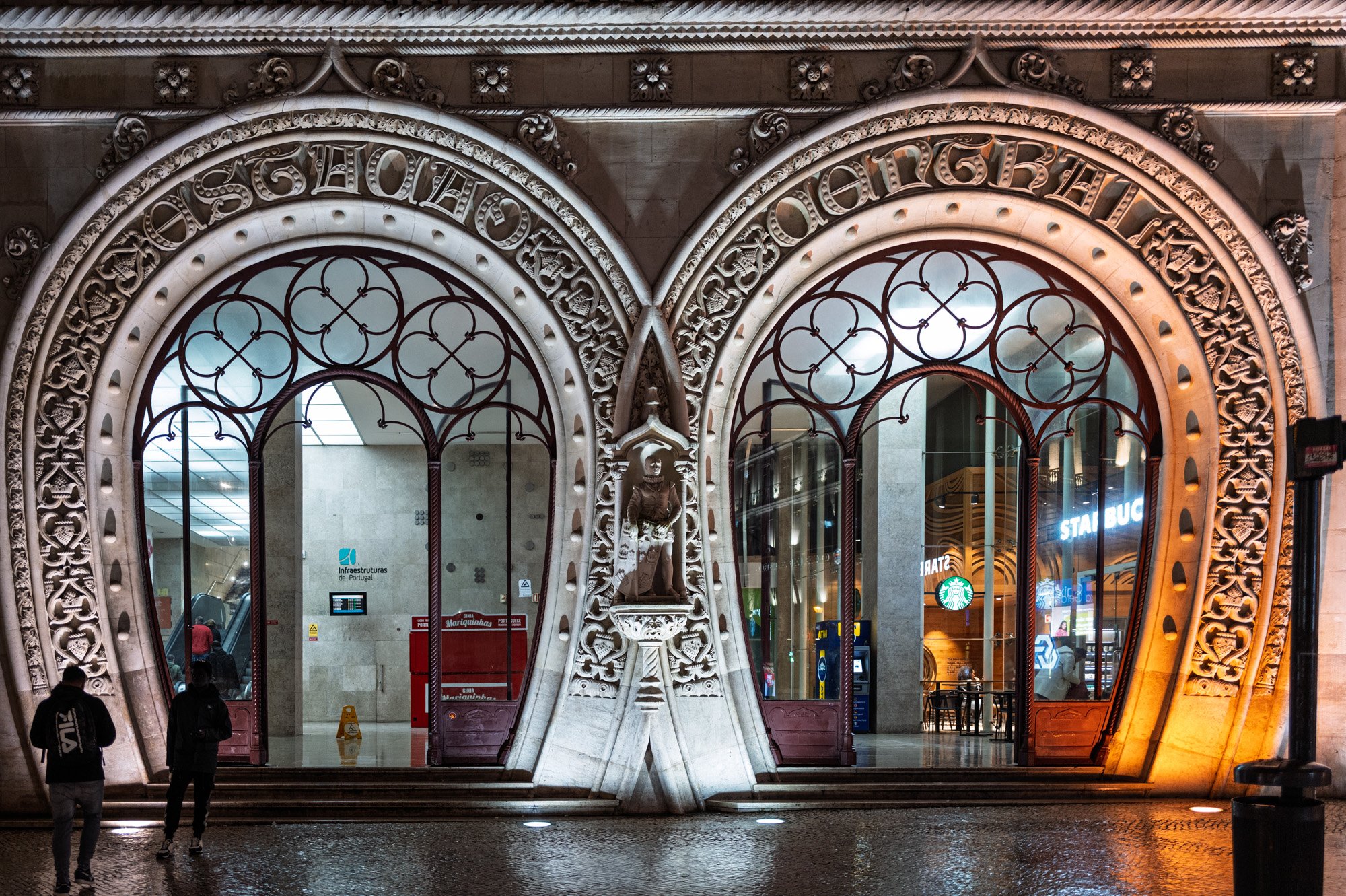 Ornate Manueline arches of Rossio Station illuminated at night with a Starbucks visible through the glass, Lisbon — bCLPhoto