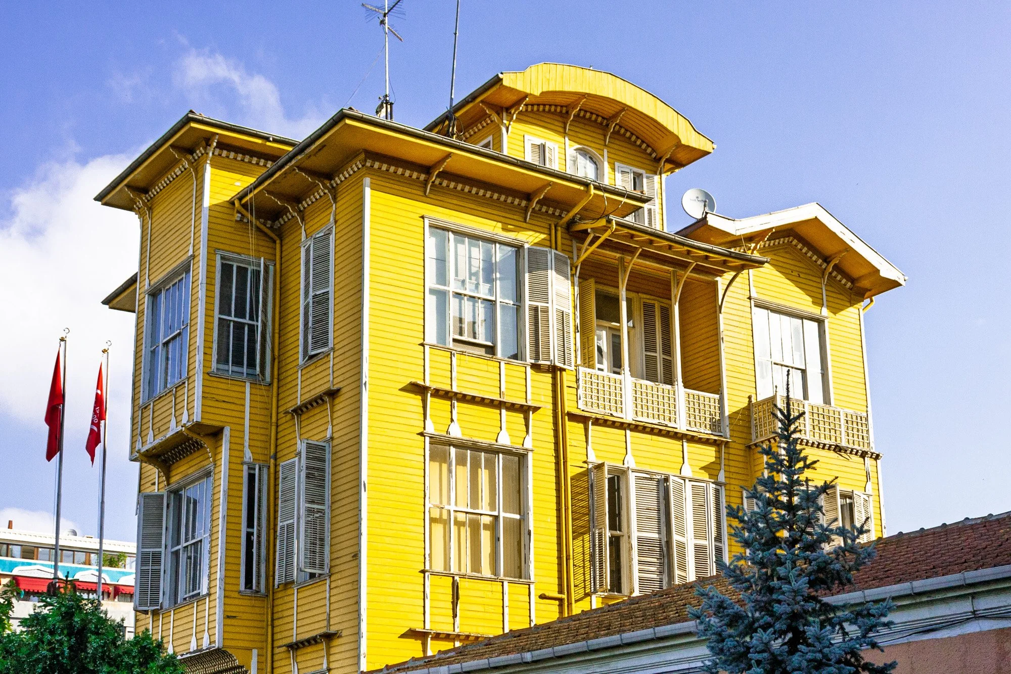Bright yellow wooden Ottoman-style house with white shutters and Turkish flags, Istanbul — bCLPhoto