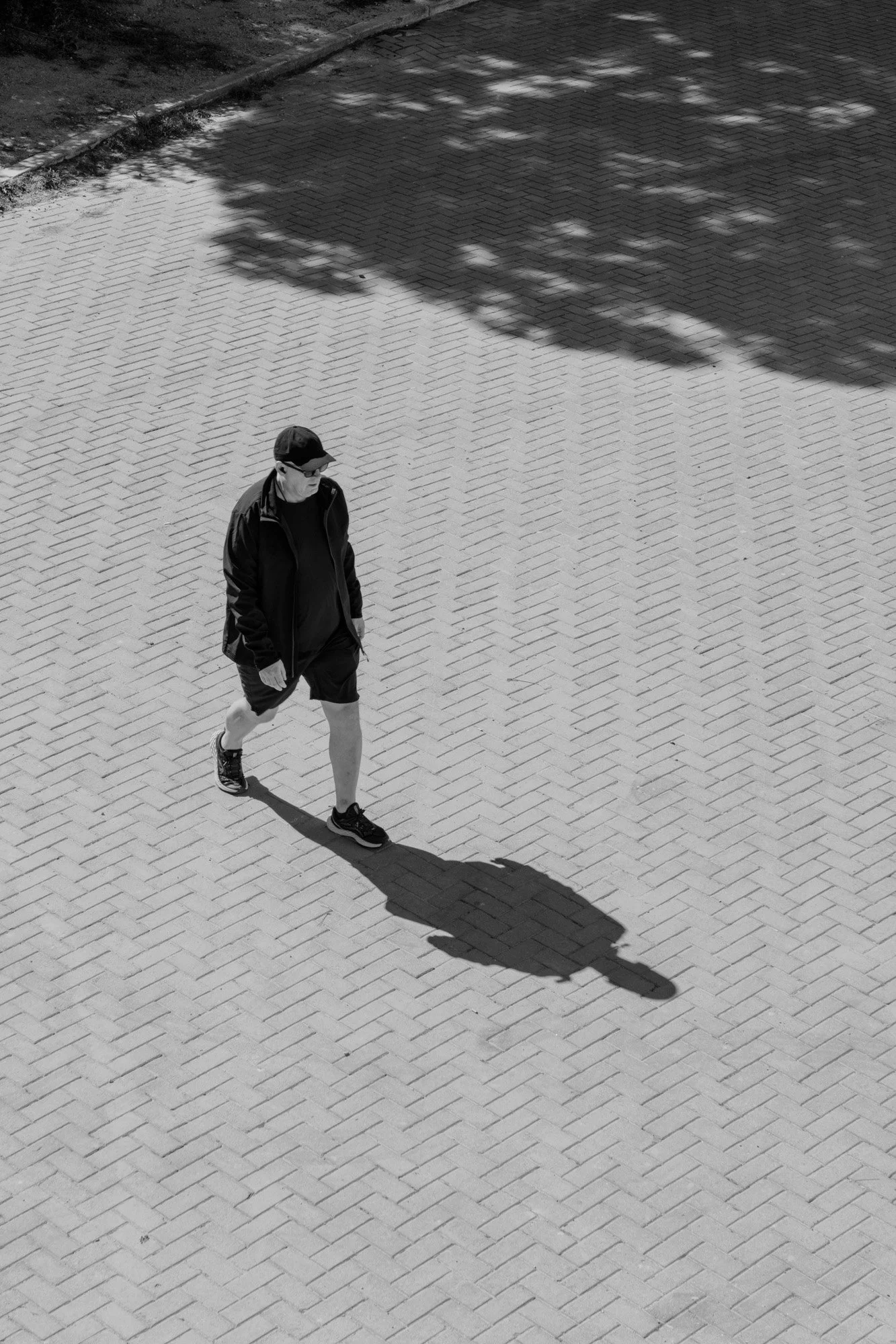 Man and his long shadow on the herringbone paving of the Olympic Ring Barcelona, aerial black and white photography — Sony a7R IV