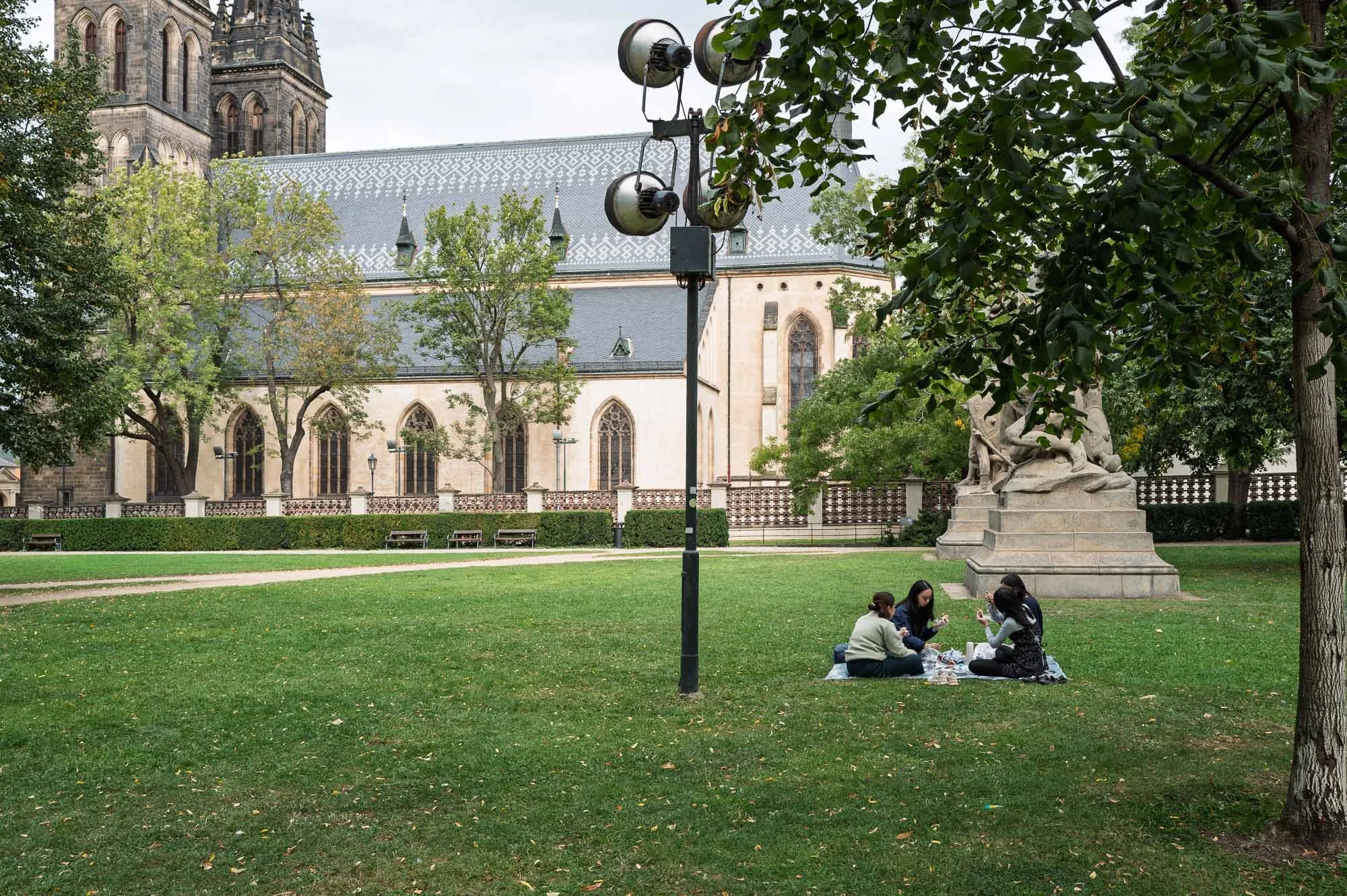 Four young women picnicking on the grass below the Basilica of St Peter and St Paul, Vyšehrad, Prague — Leica Q3