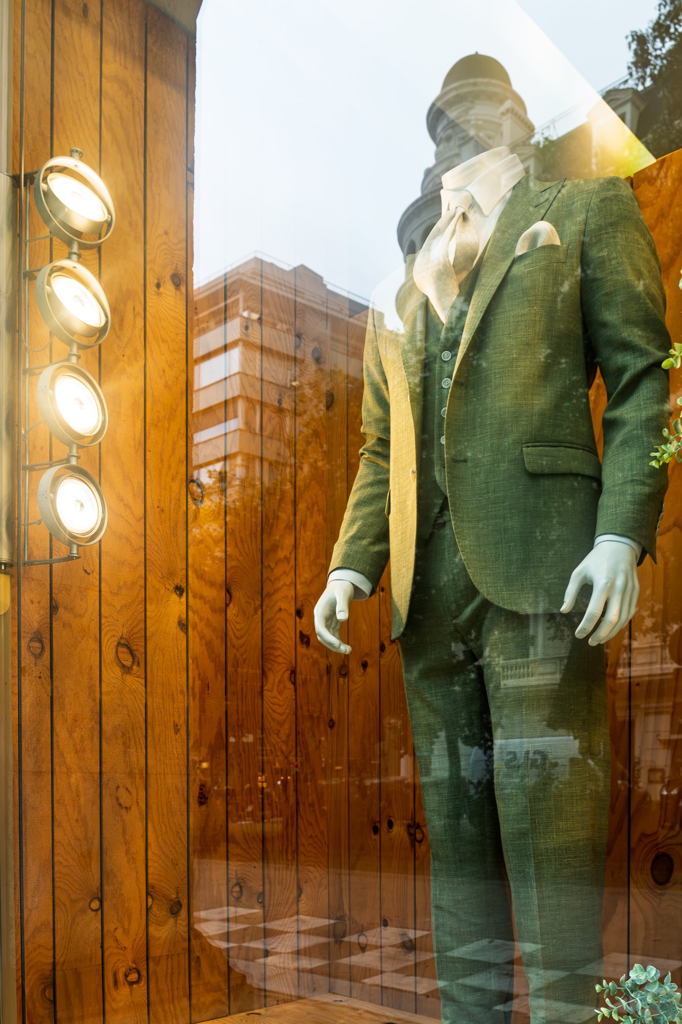 Headless mannequin in a green suit reflecting a Barcelona building, street photography — Sony A7R IV