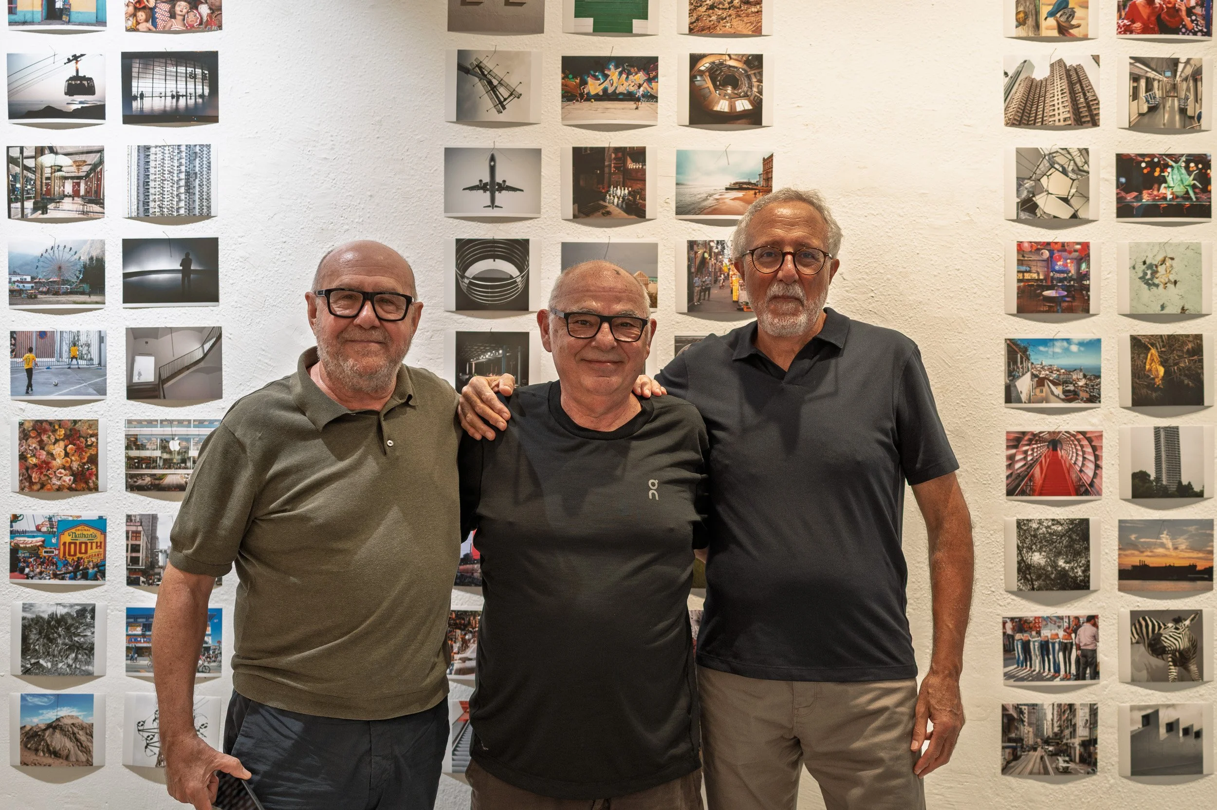 Photographers Jordi Comes, Cosme Lapena and Benet Solina in front of a wall of prints at the 100x100PHOTO exhibition, espai [b], Barcelona, October 2026.