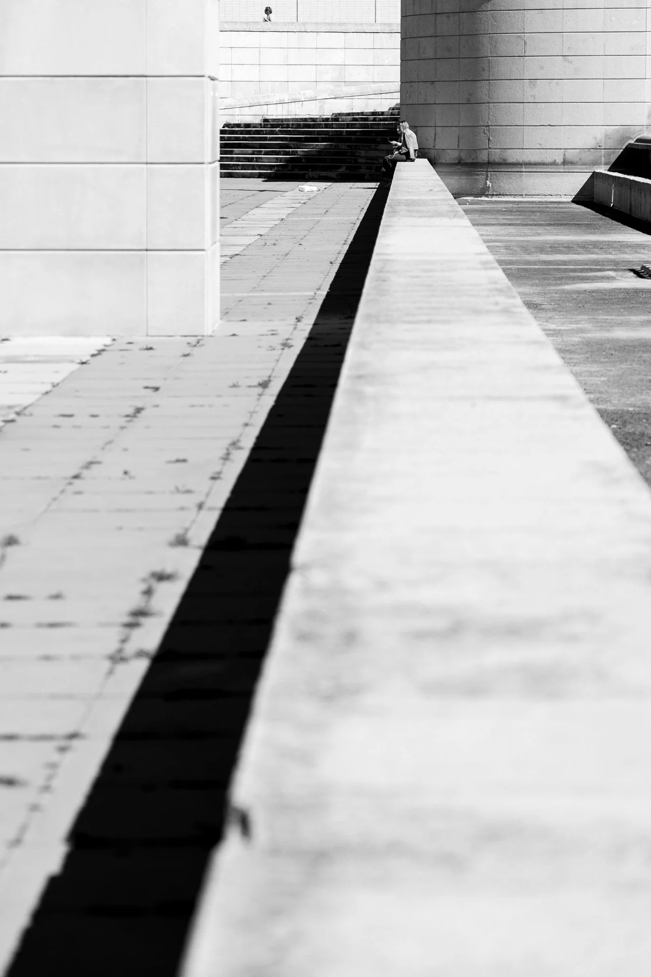 Diagonal shadow line with distant figure, Barcelona plaza — Sony A7R IV