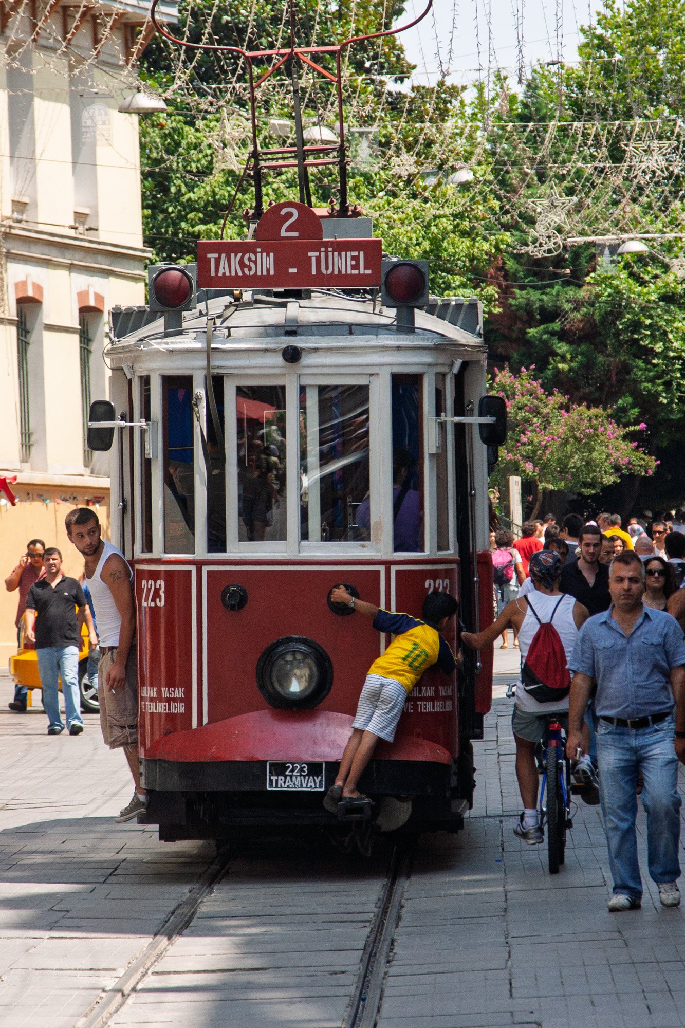Young boy hanging off the front of the historic red Taksim-Tünel tram on İstiklal Avenue, Istanbul — bCLPhoto