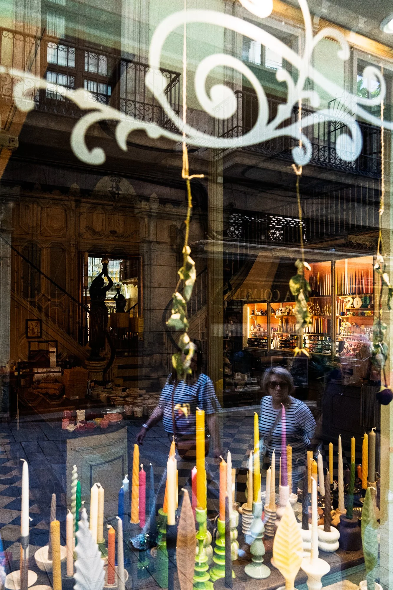 Two women in matching striped shirts reflected among candles, Barcelona — Sony A7R IV