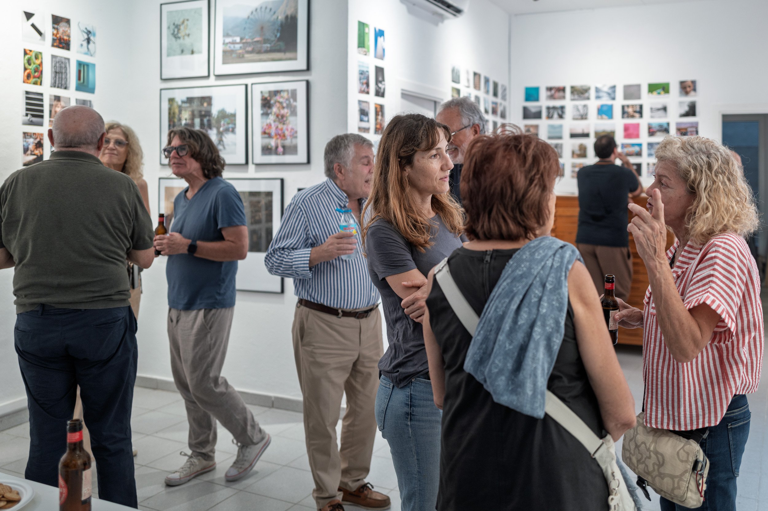 Visitors talking among framed and small prints at the 100x100Photo opening, Barcelona — Leica Q3
