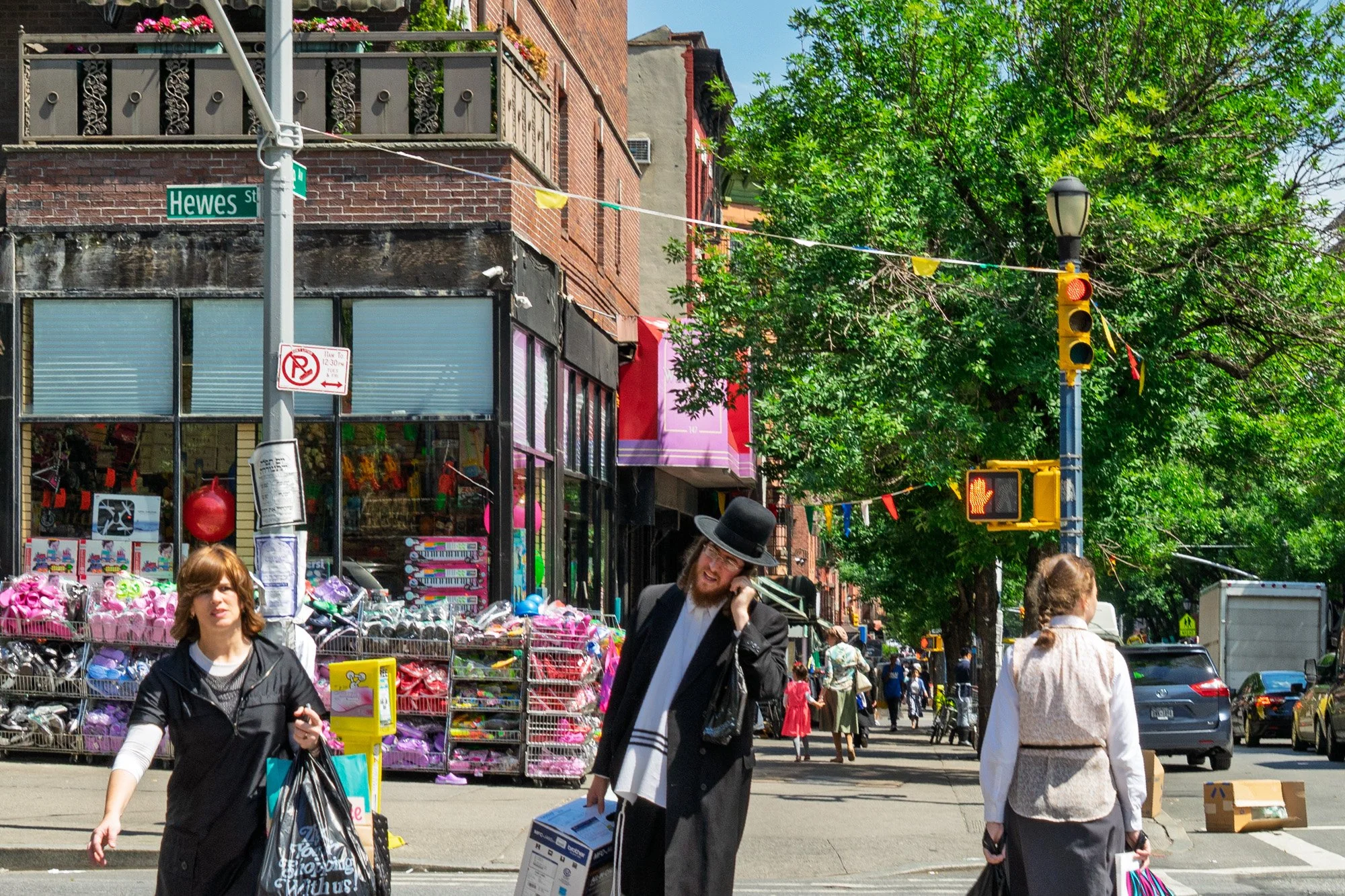 Man on phone with tallit on Hewes Street, colorful shop fronts, South Williamsburg Brooklyn — Sony a7II
