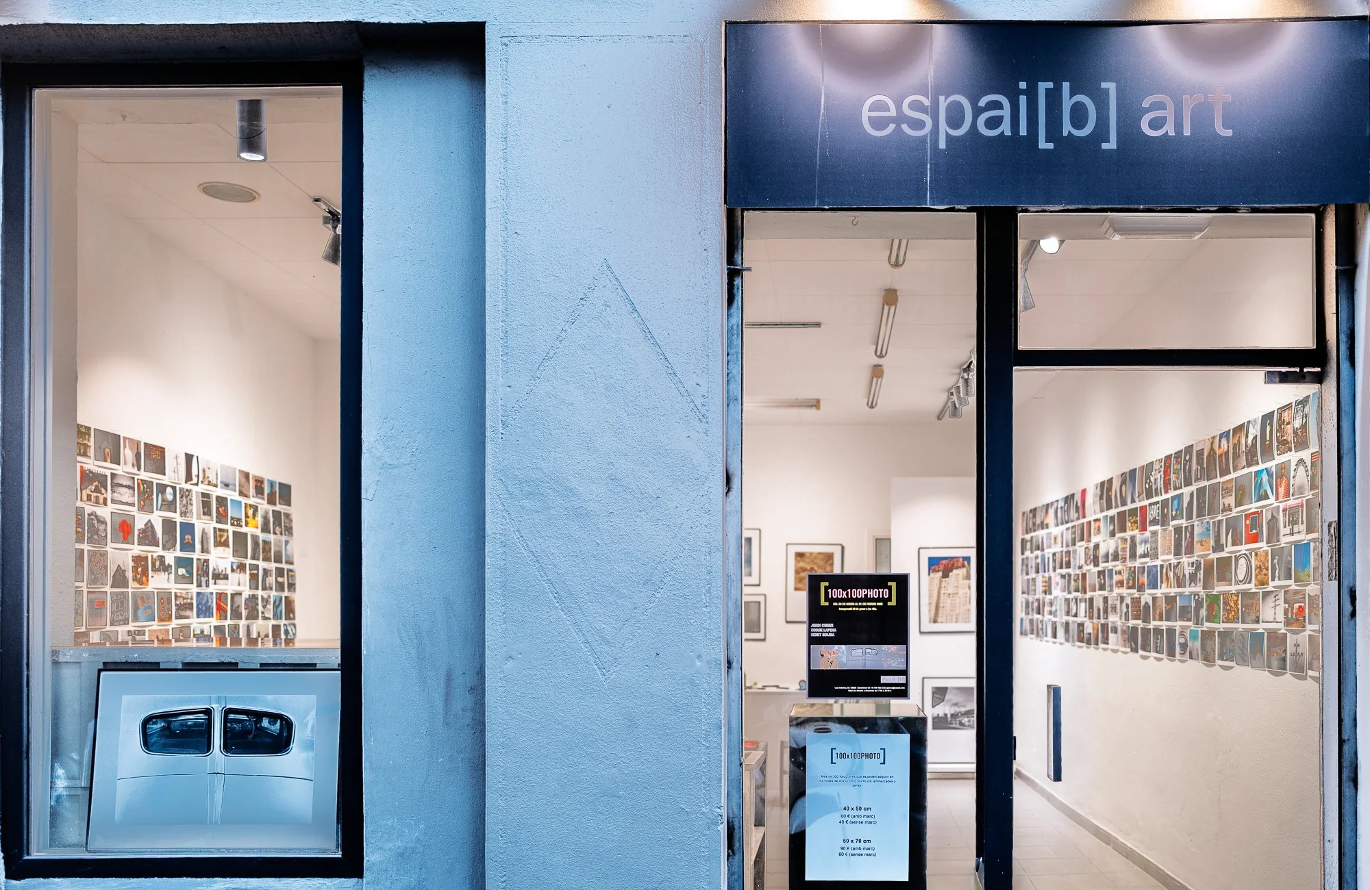 Espai [b] gallery storefront at dusk, Barcelona, during the 100x100PHOTO exhibition, January 2025