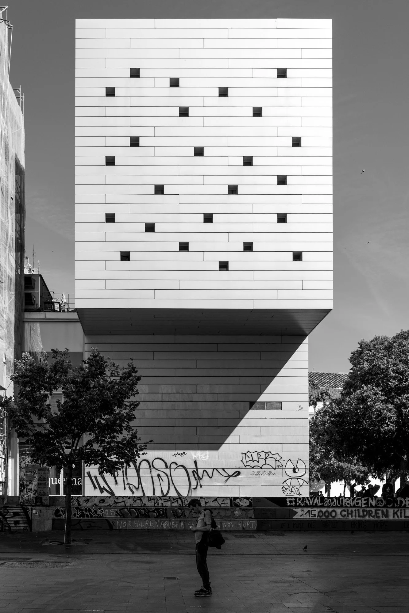 White building over graffiti walls, man on phone, El Raval — Sony A7R IV