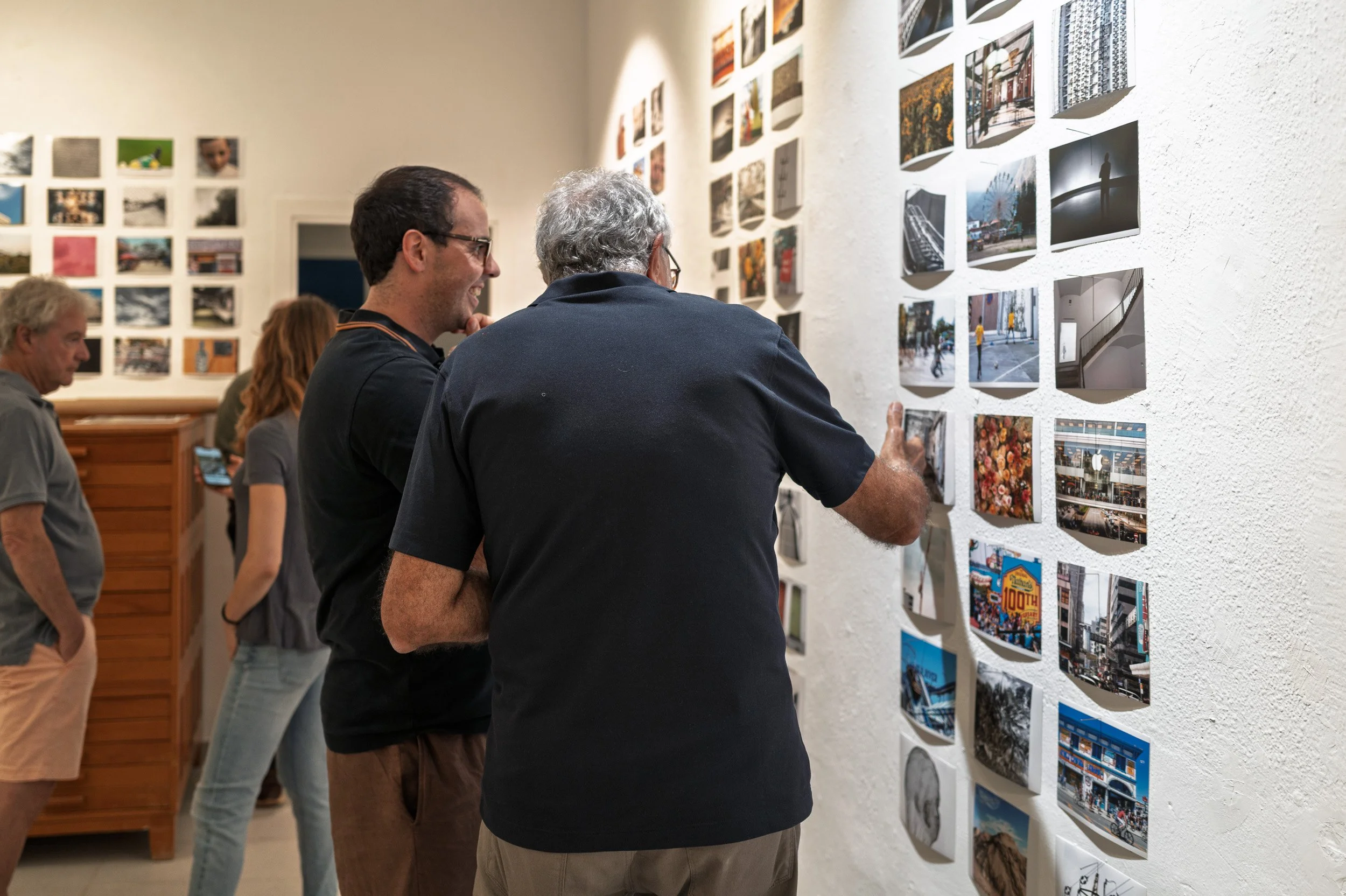 Man smiling beside a friend with his hand on a print, espai[b] gallery, Barcelona — Leica Q3