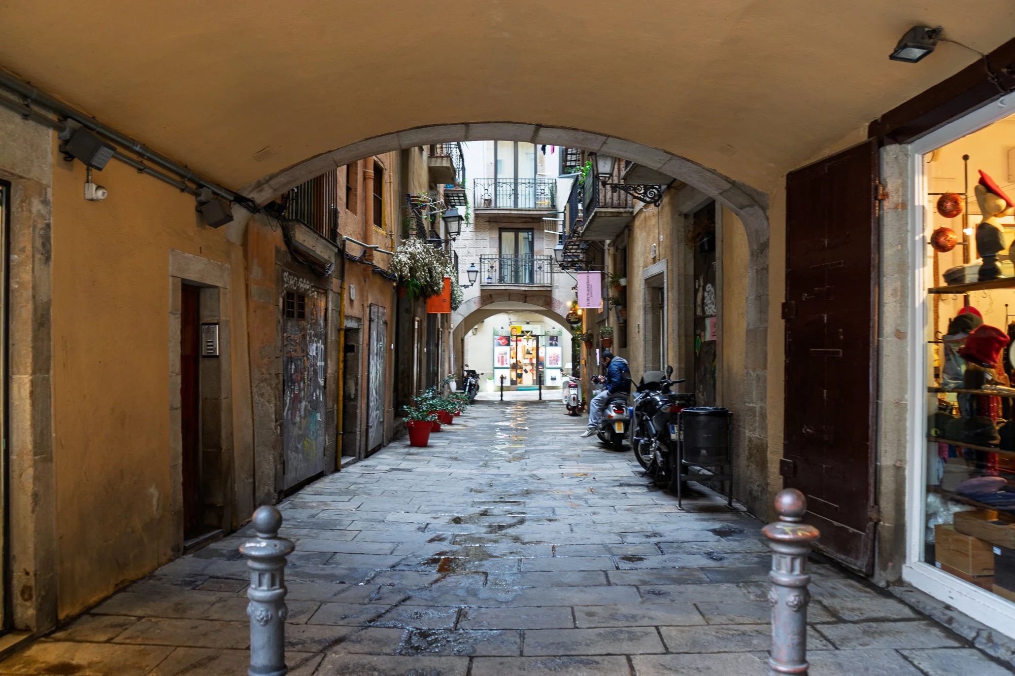 Narrow stone archway with parked motorbikes in El Born, Barcelona — Leica Q3