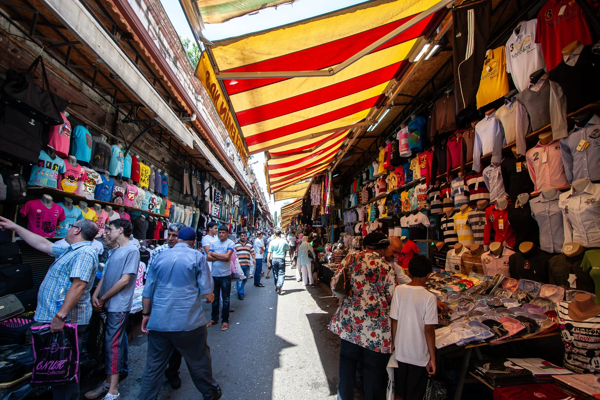 Red and yellow striped awnings over a crowded clothing street near Mahmutpaşa, Istanbul — Canon EOS 40D