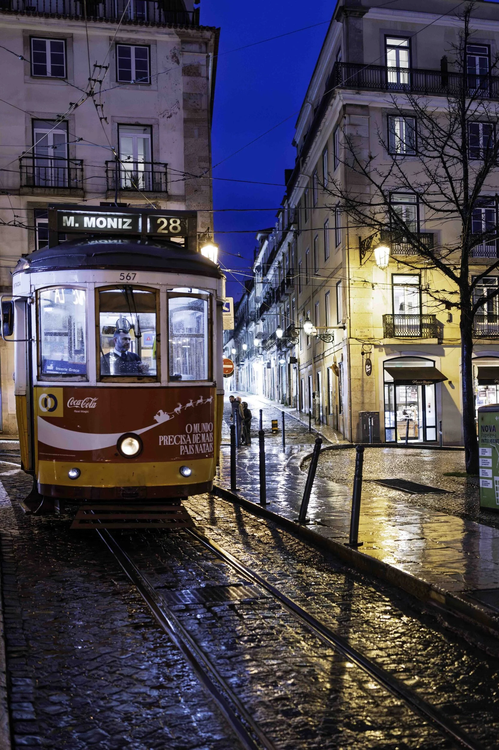 Tram 28 at blue hour on wet cobblestones, Lisbon street photography at night — Leica Q3