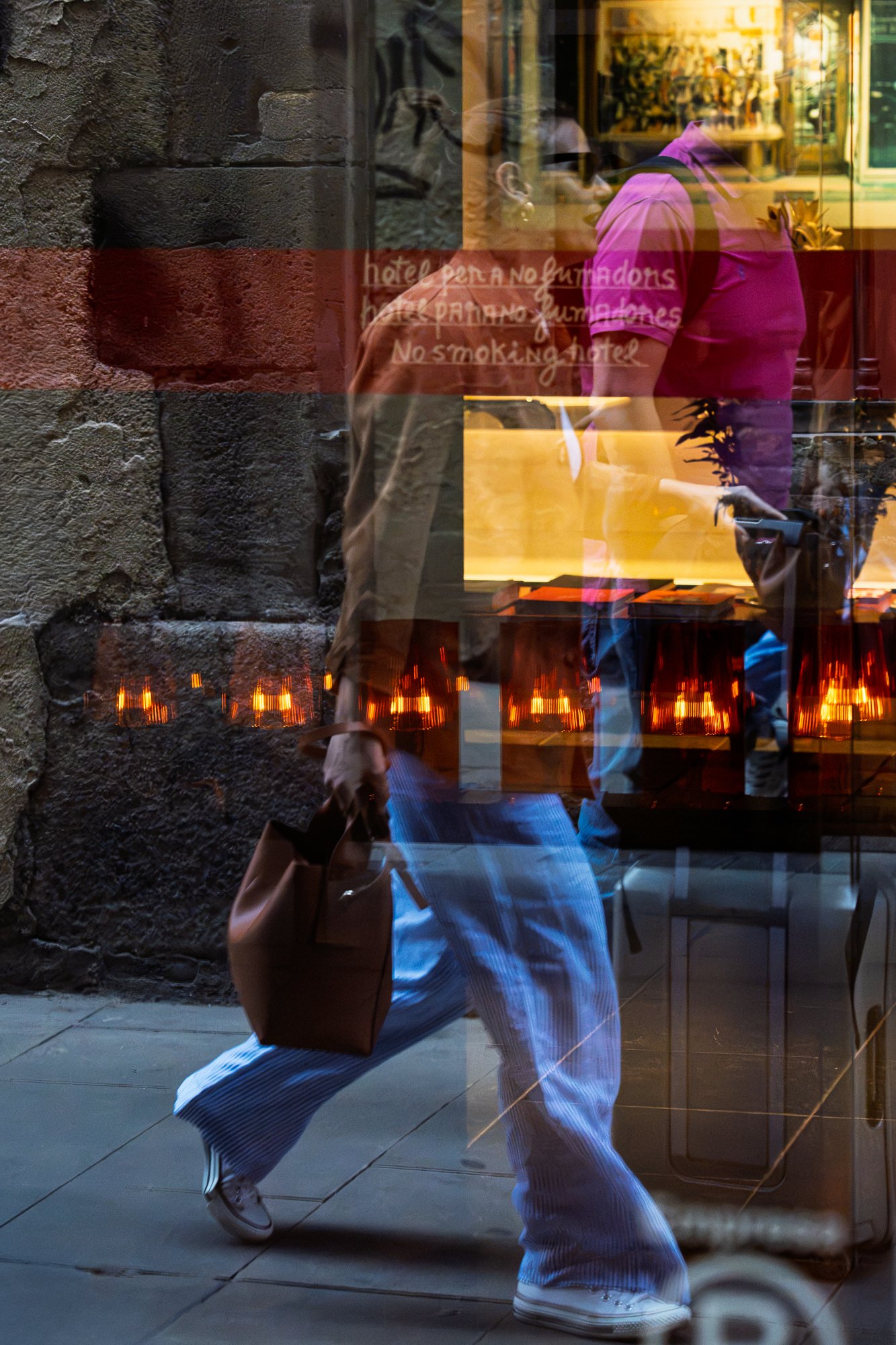 Bilingual "no smoking hotel" sign reflected with a passerby, street photography in Barcelona – bCLPhoto