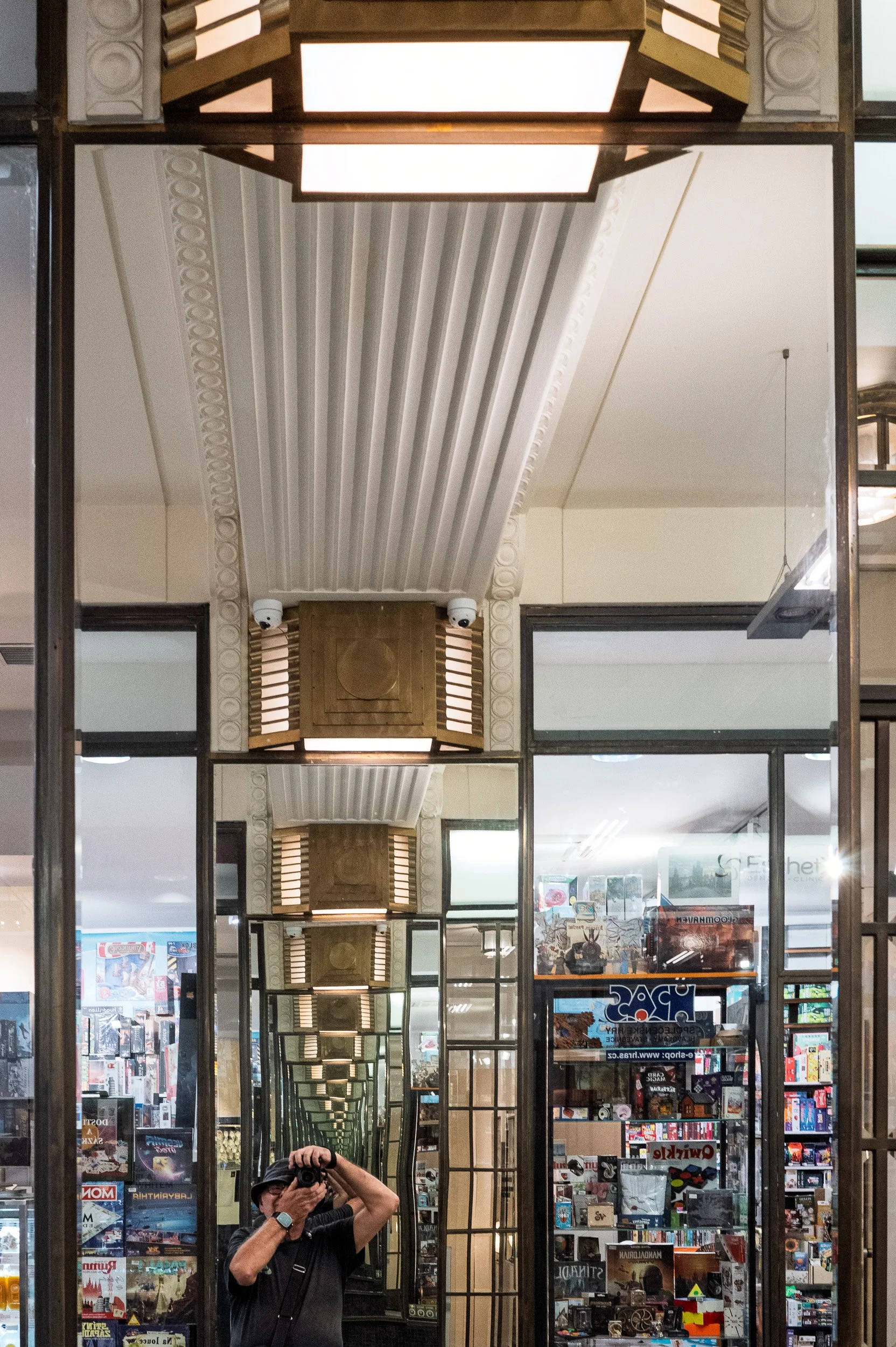 Photographer's self-portrait in a mirrored pillar, lanterns repeating, Lucerna passage, Prague — Leica Q3