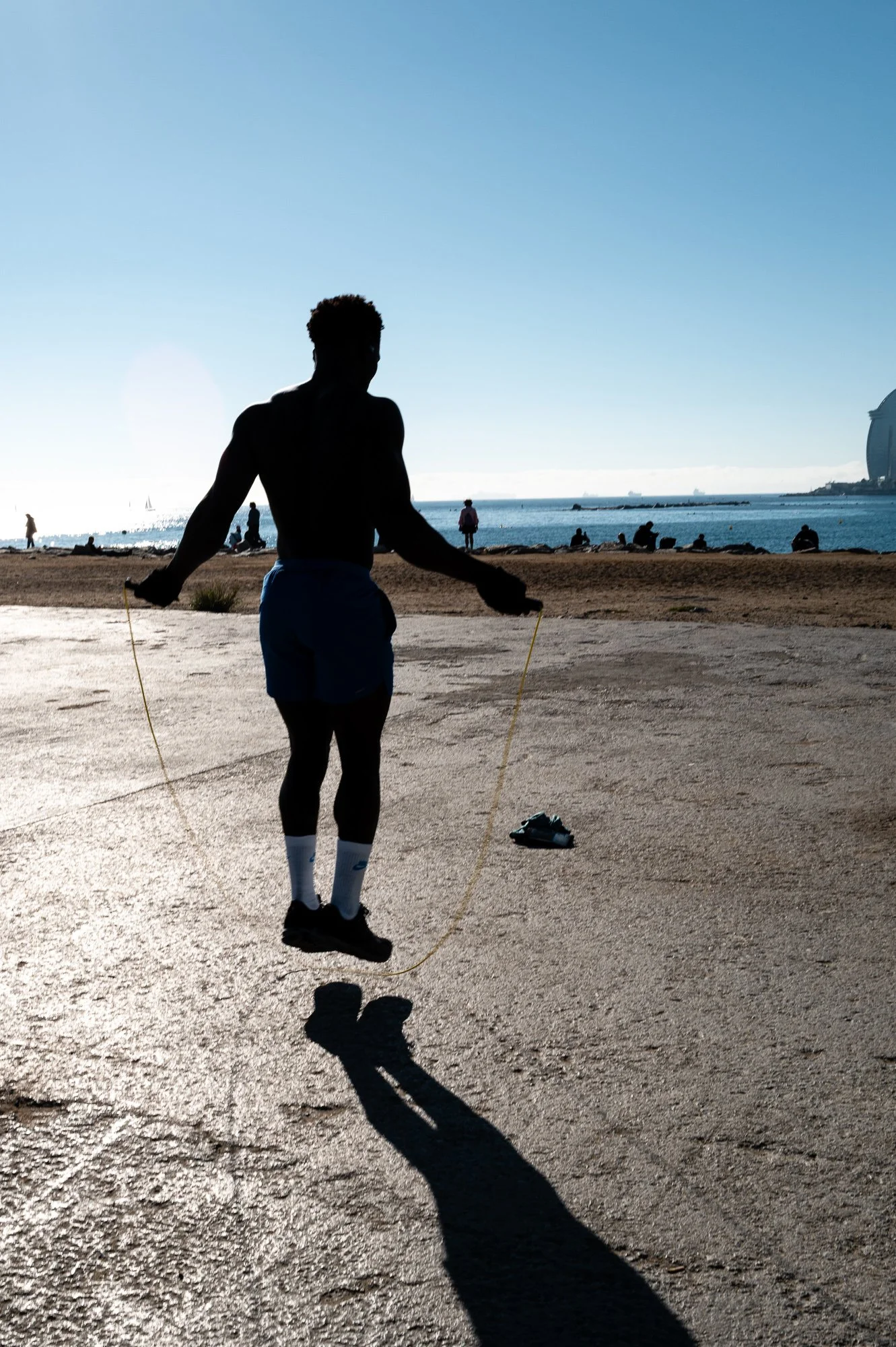 Silhouette of a man jumping rope against the sun on Barceloneta beach — Leica Q3