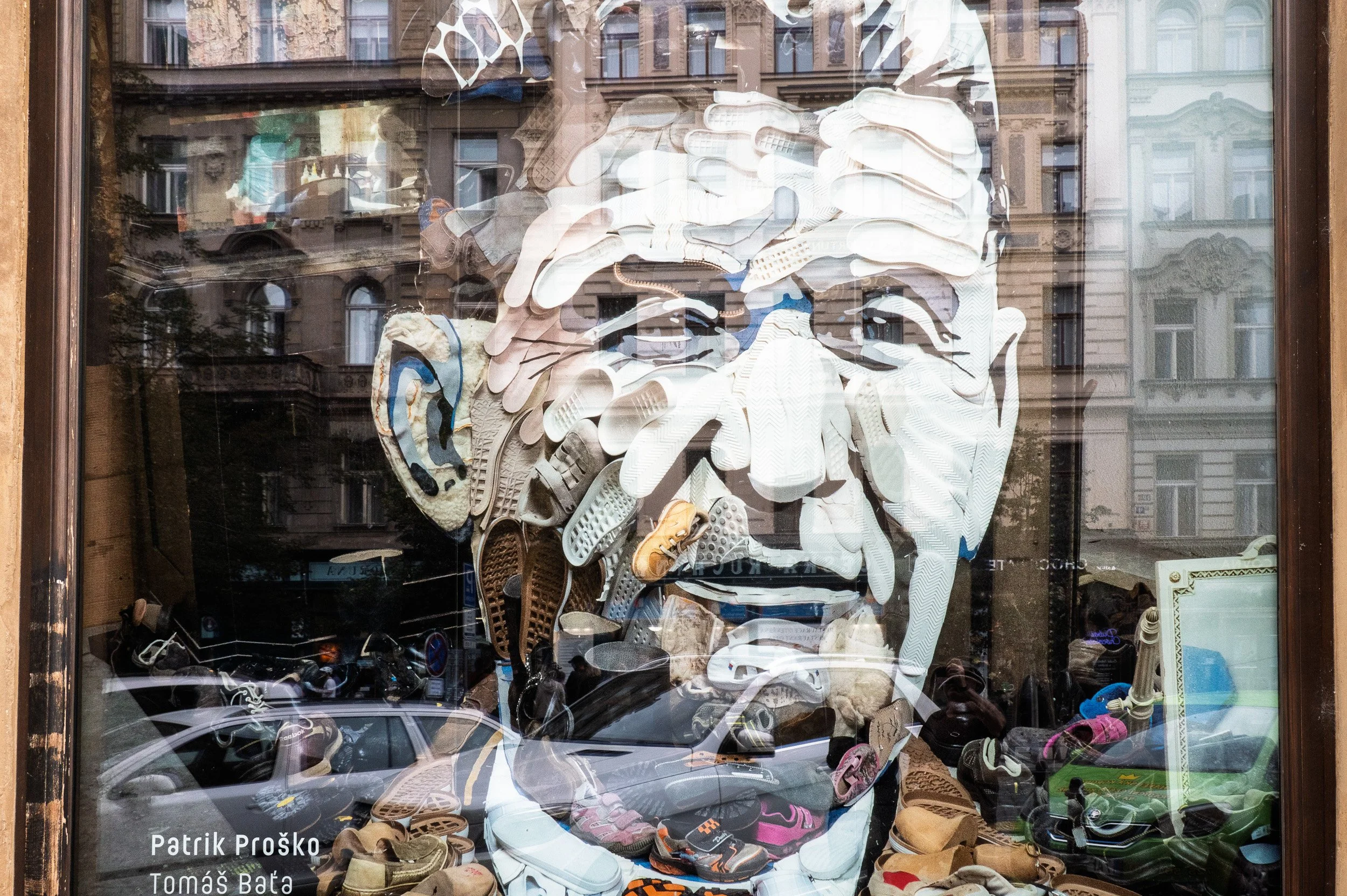 Patrik Proško's Tomáš Baťa portrait made of shoes, Old Town façades reflected in the glass, Prague — Leica Q3