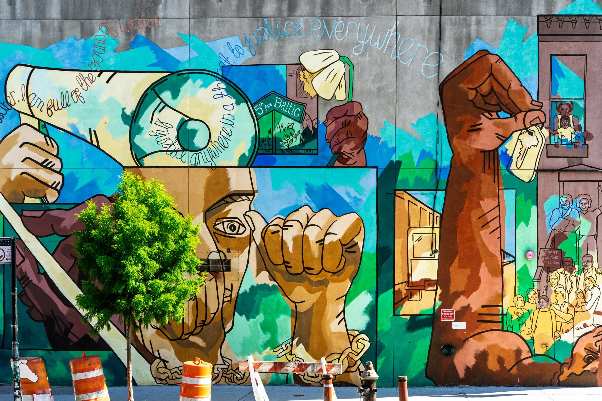 Community mural with raised fists and justice text on a wall in Bed-Stuy, Brooklyn — Sony a7II