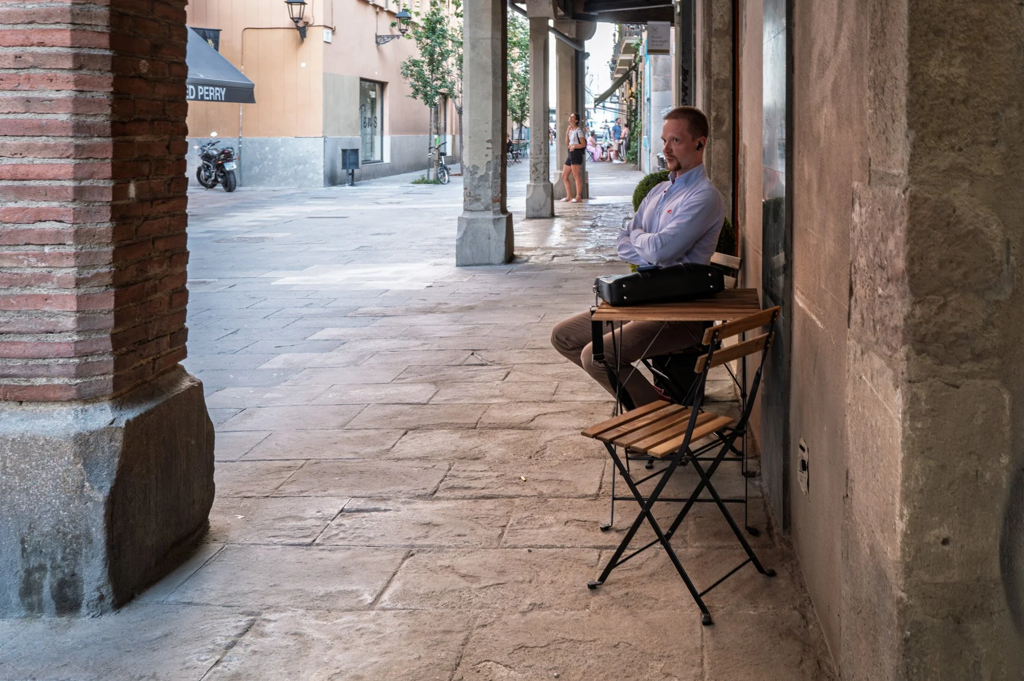 Man resting with a violin case on a bench in El Born, Barcelona — Leica Q3