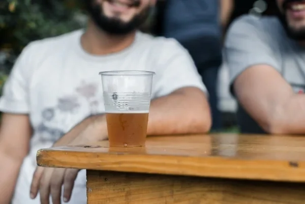 Plastic cup of beer on a table in front of a man