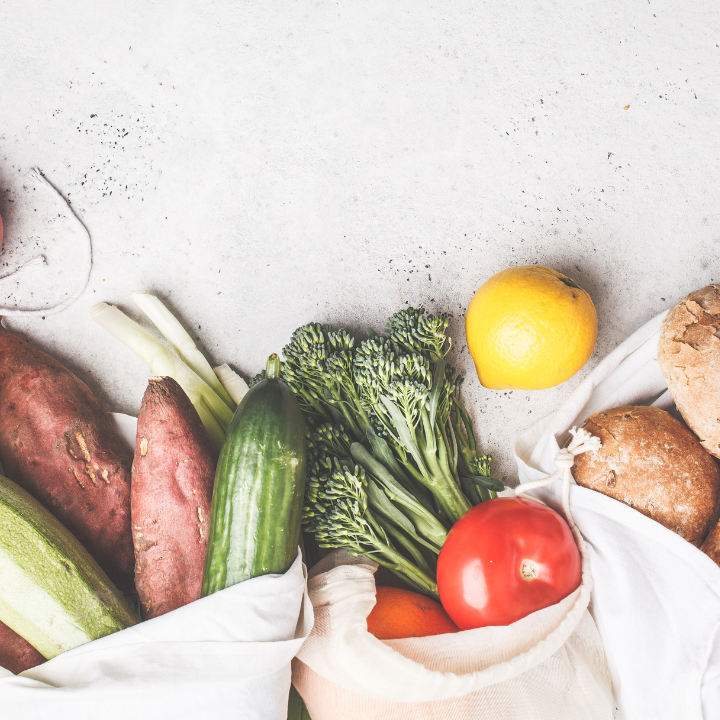 Assorted fresh vegetables and a lemon on a light surface.