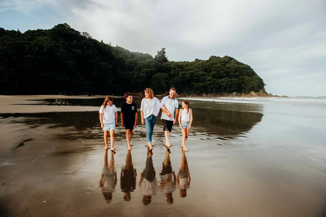 Family walking along Waihi beach during family photo session 