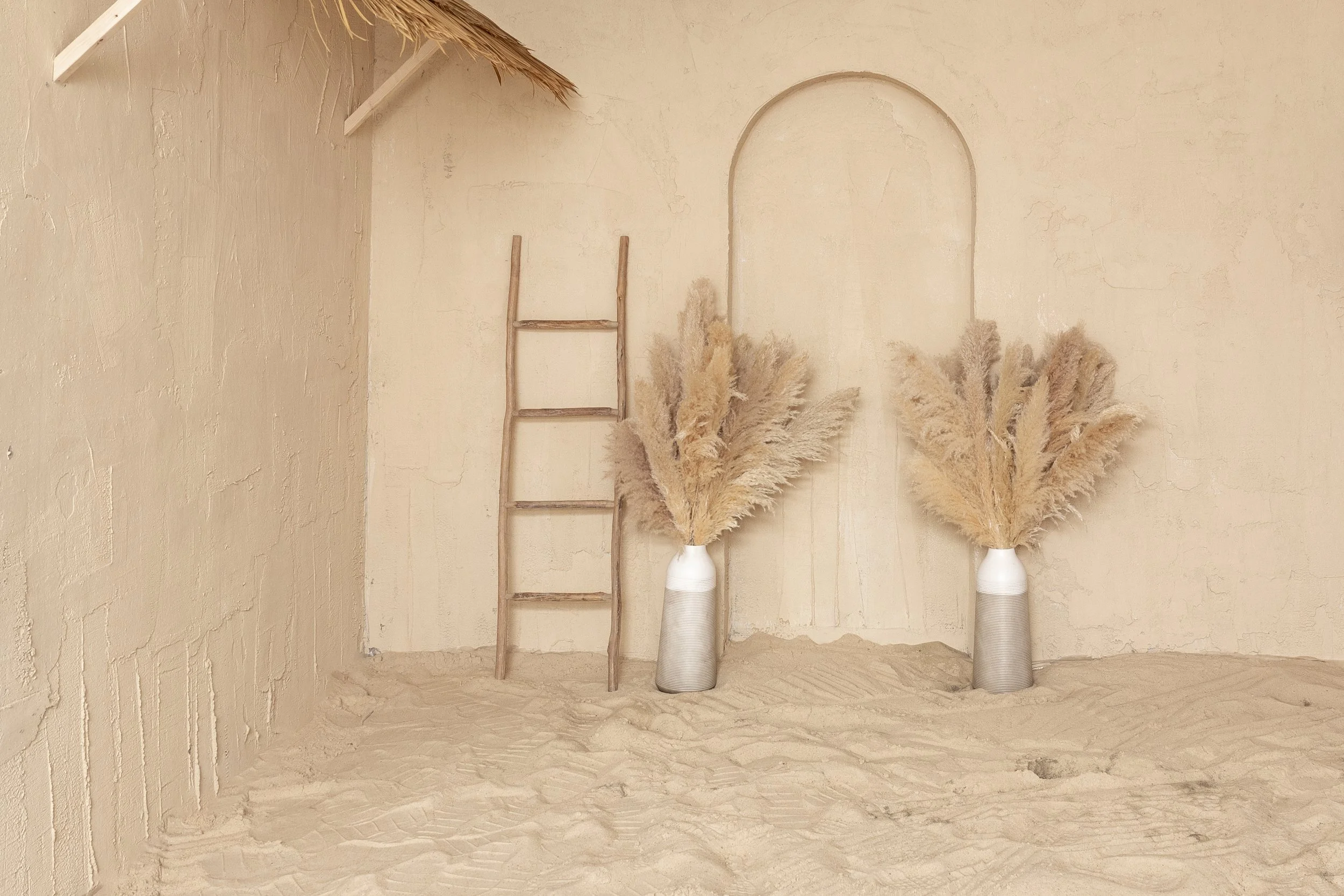 Beach Set with neutral colored walls lush sand and a thatch roof