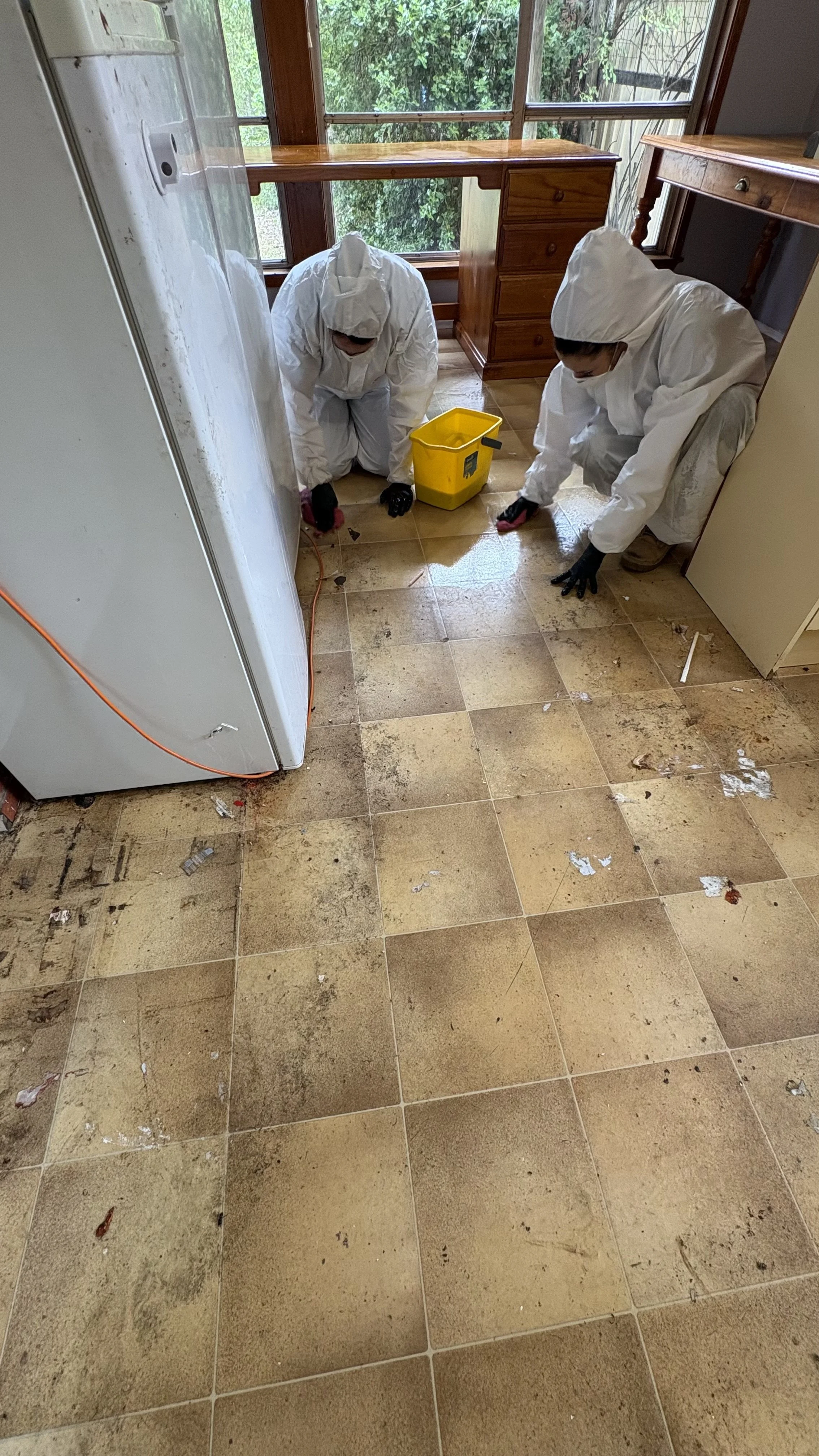 Person wearing gloves, mask, and glasses cleaning or maintaining an oven by removing or adjusting the oven rack.