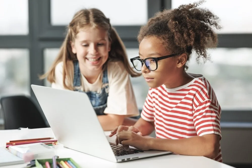 Two female elementary students using a laptop to study in a special education school