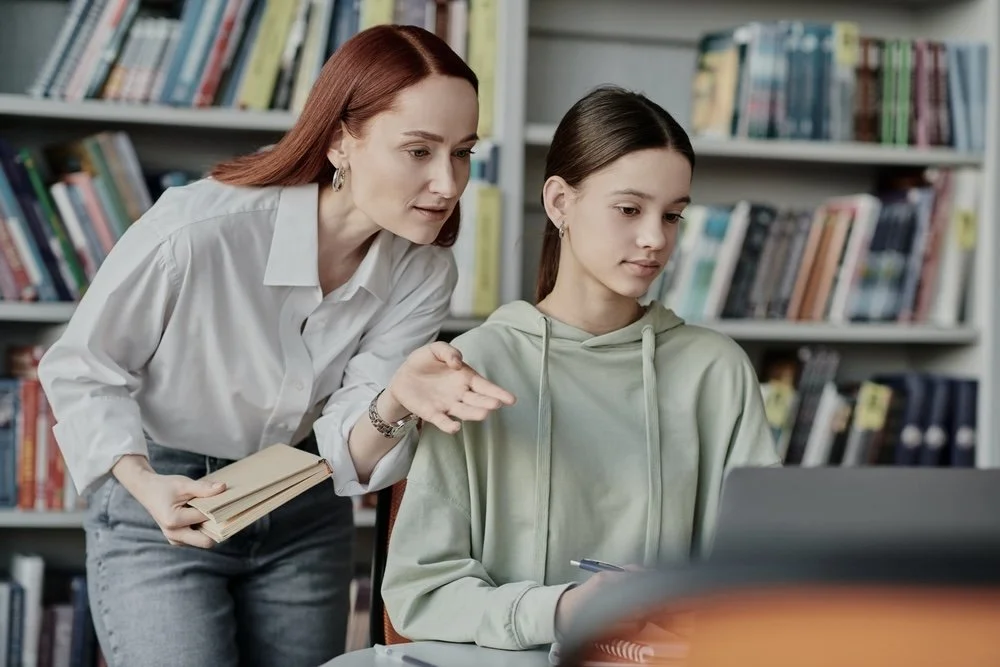 Woman teaching a girl in a library