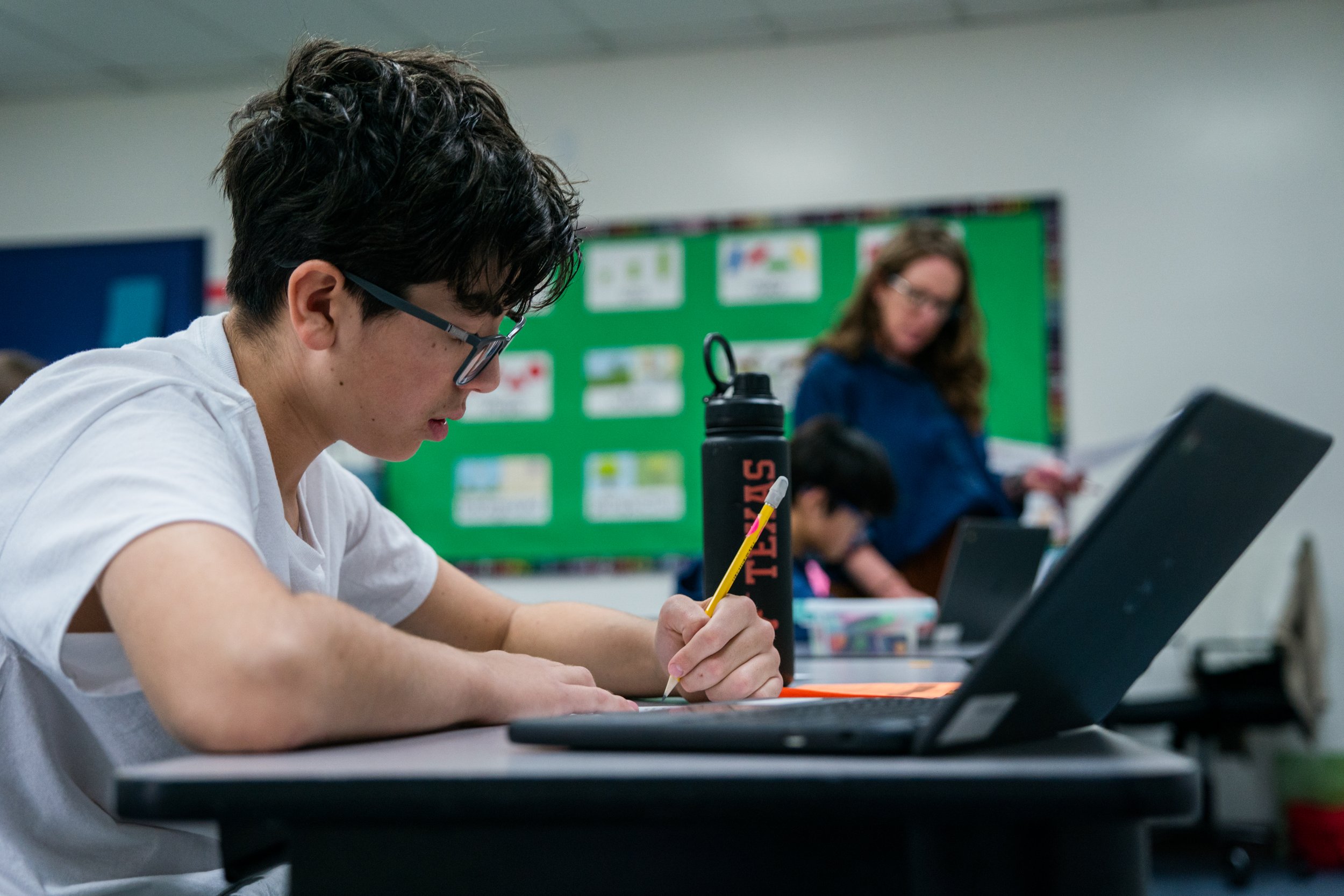 Pathway student writing notes beside his laptop during Learning Center time