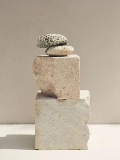 Stack of textured stones on beige blocks against a neutral background