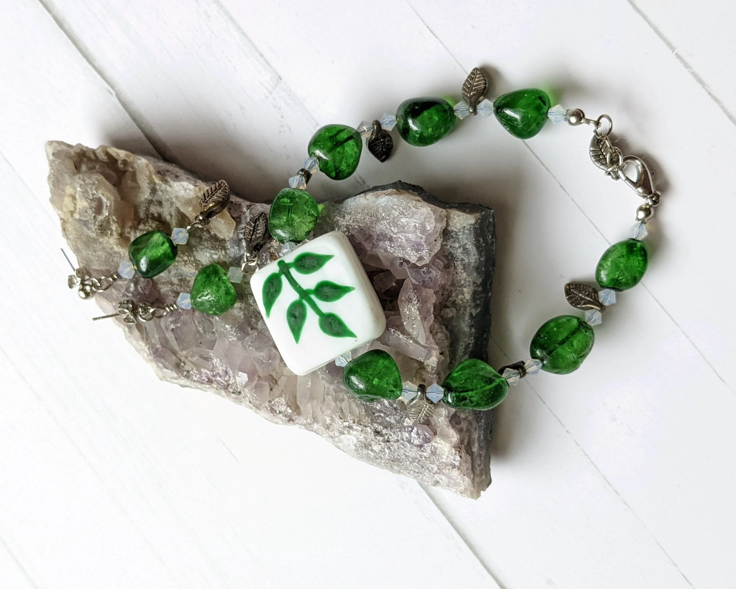 Green Aventurine bracelet and earrings on an Amethyst geode slice. White board background