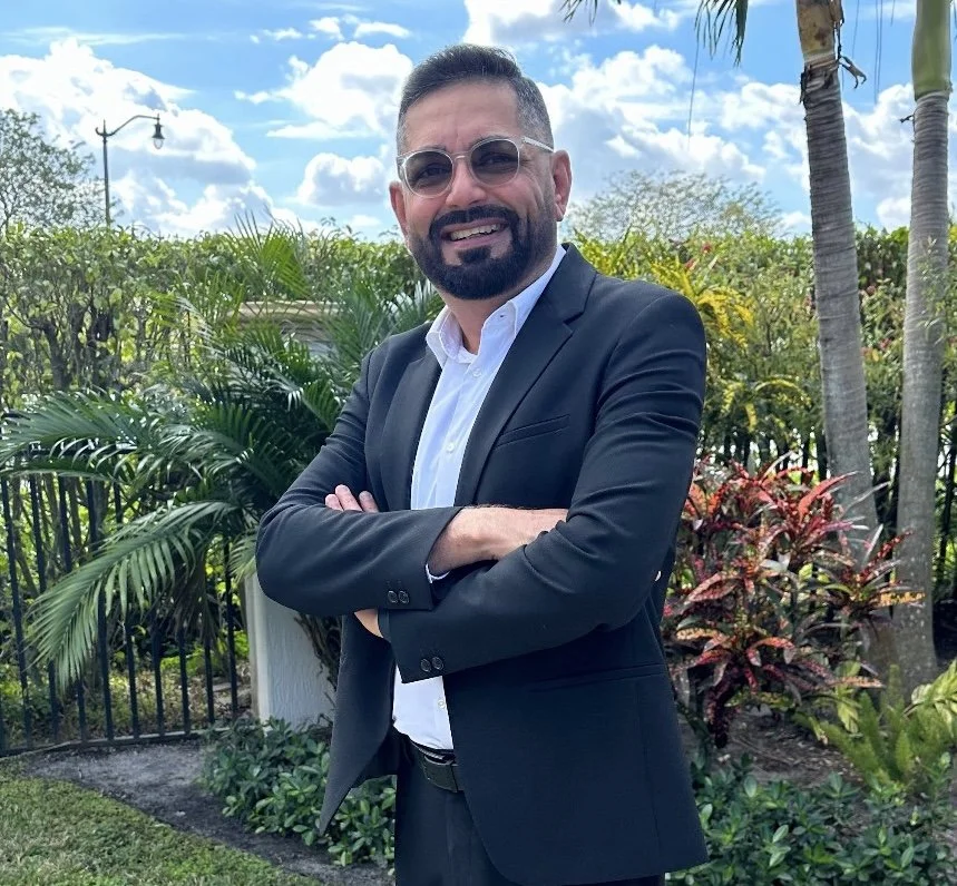 Headshot of Hardeep Anand outdoors in front of green palm trees