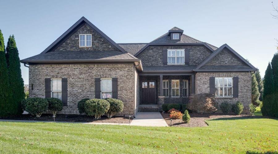 Home with a medium-toned grey brick with dark grey shutters and roof.