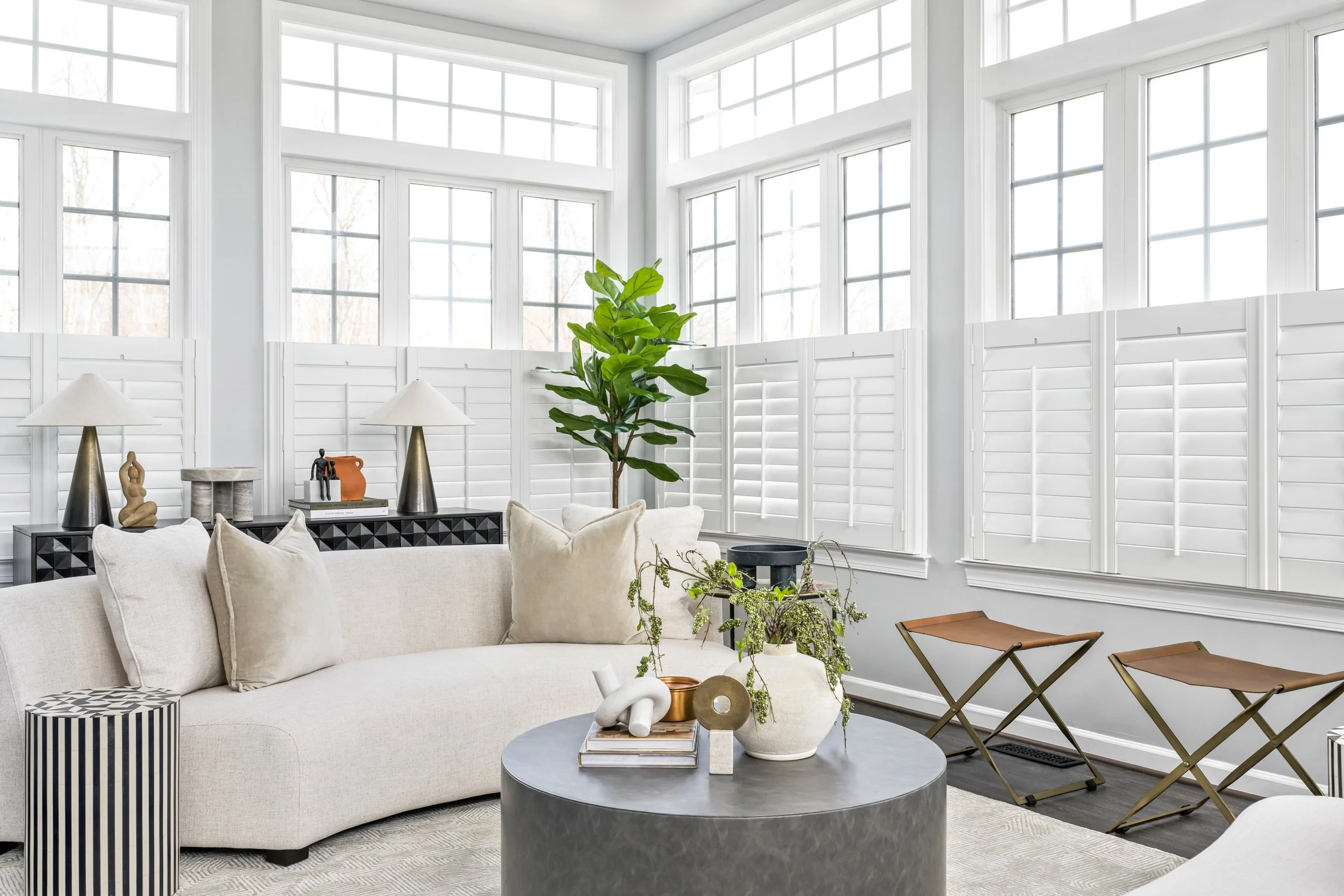 Bright, modern living room with white walls, large windows, and white plantation shutters in Maryland.