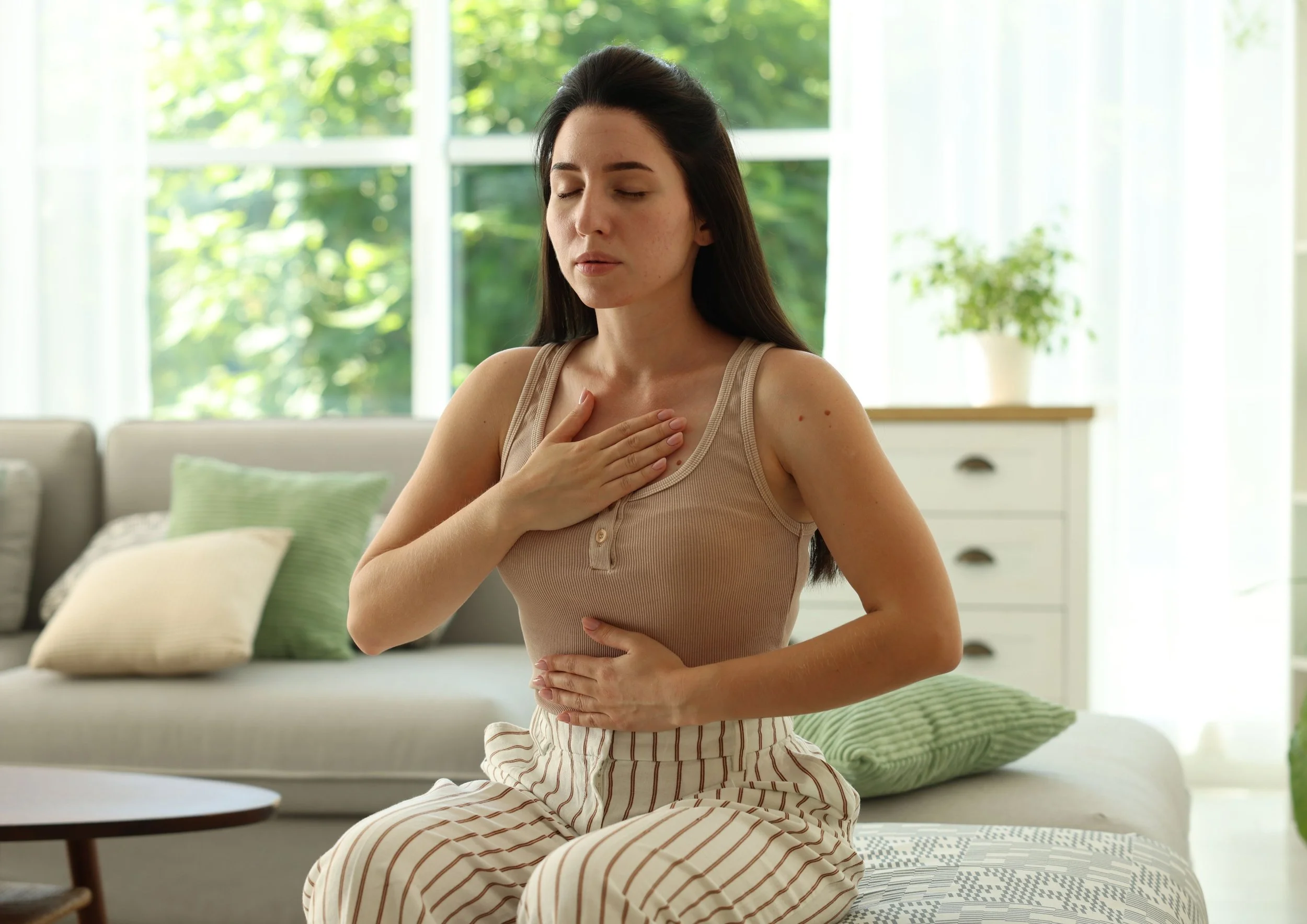 A close-up shot of a person wearing a soft pink sweater with their hands gently layered over their heart in a somatic calming gesture, featured on a Jondi Whitis blog post graphic titled "When Stress Hits Fast: A Simpler Way to Reset."