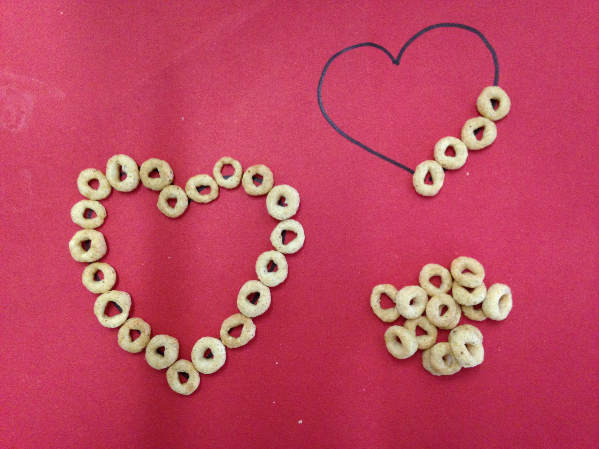Gluing cheerios on a heart outline