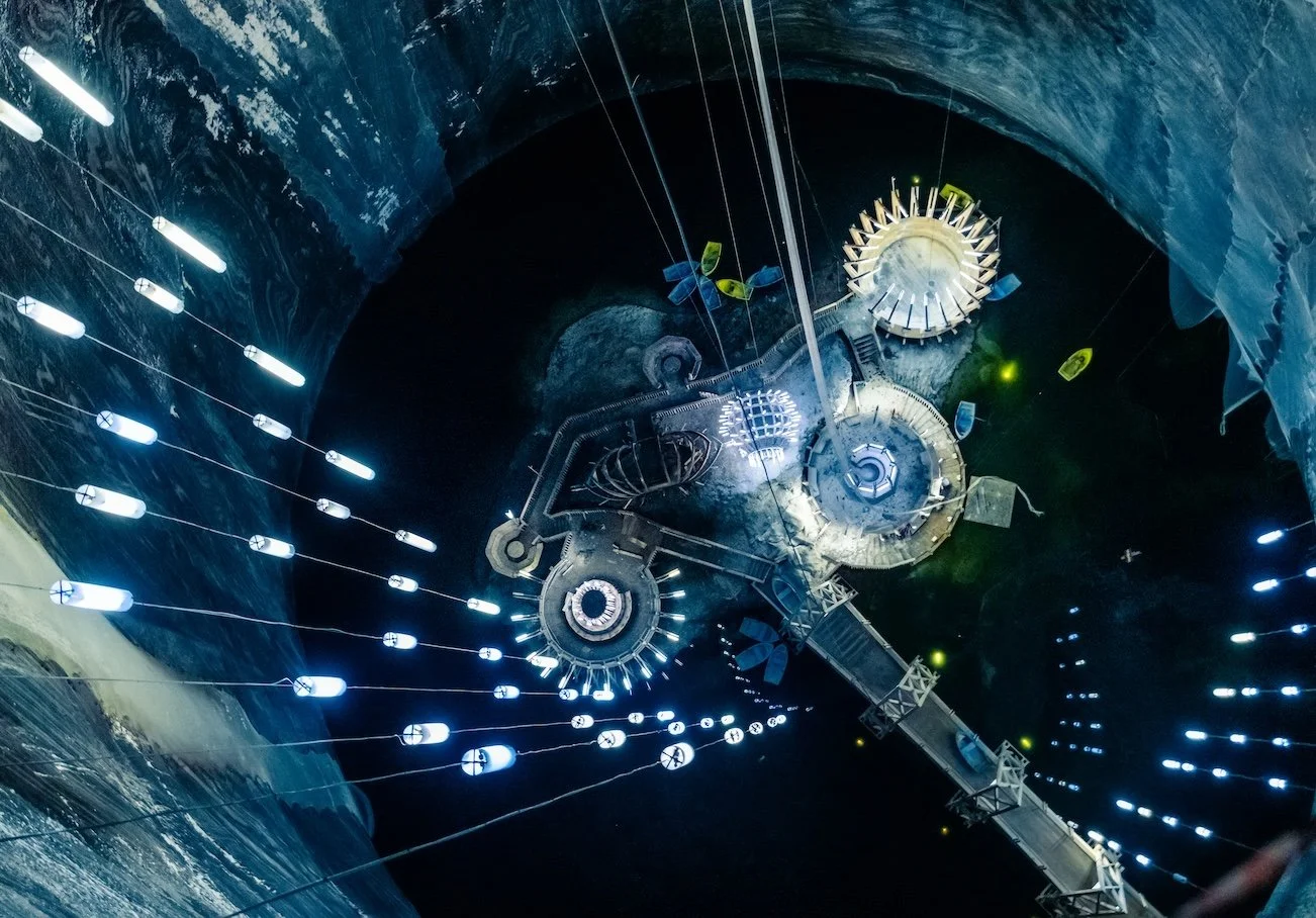 View of a space station orbiting Earth from below, showing solar panels and structural components, with Earth’s surface visible in the background.