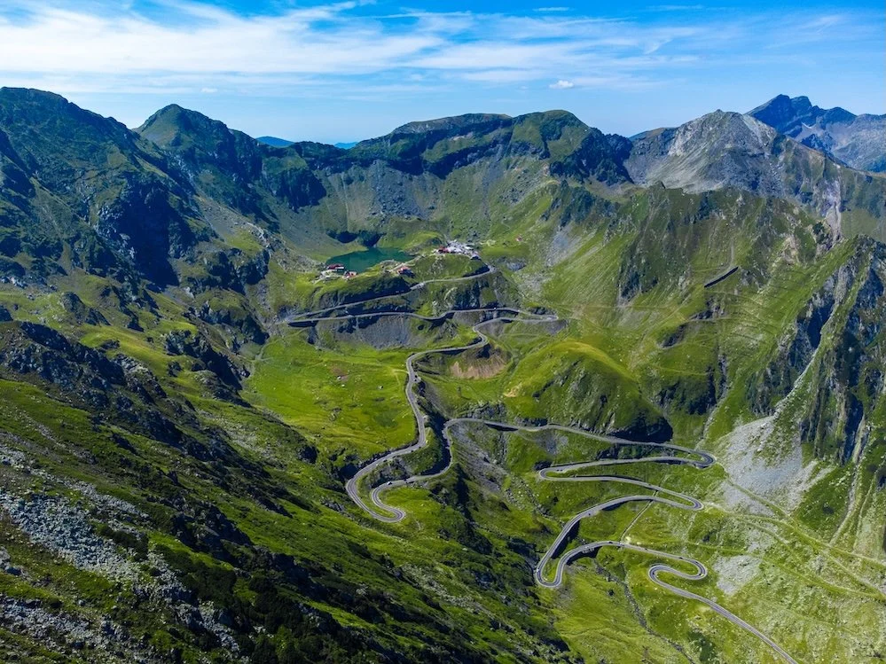 Mountain landscape with steep, winding roads and small buildings on the hillside.