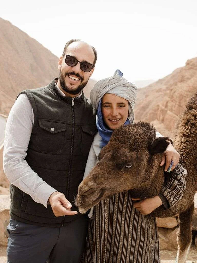 Man with young child embracing a camel
