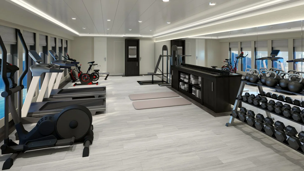 Interior view of Magellan Discoverer fitness room with weights, cadrio machines, and mats