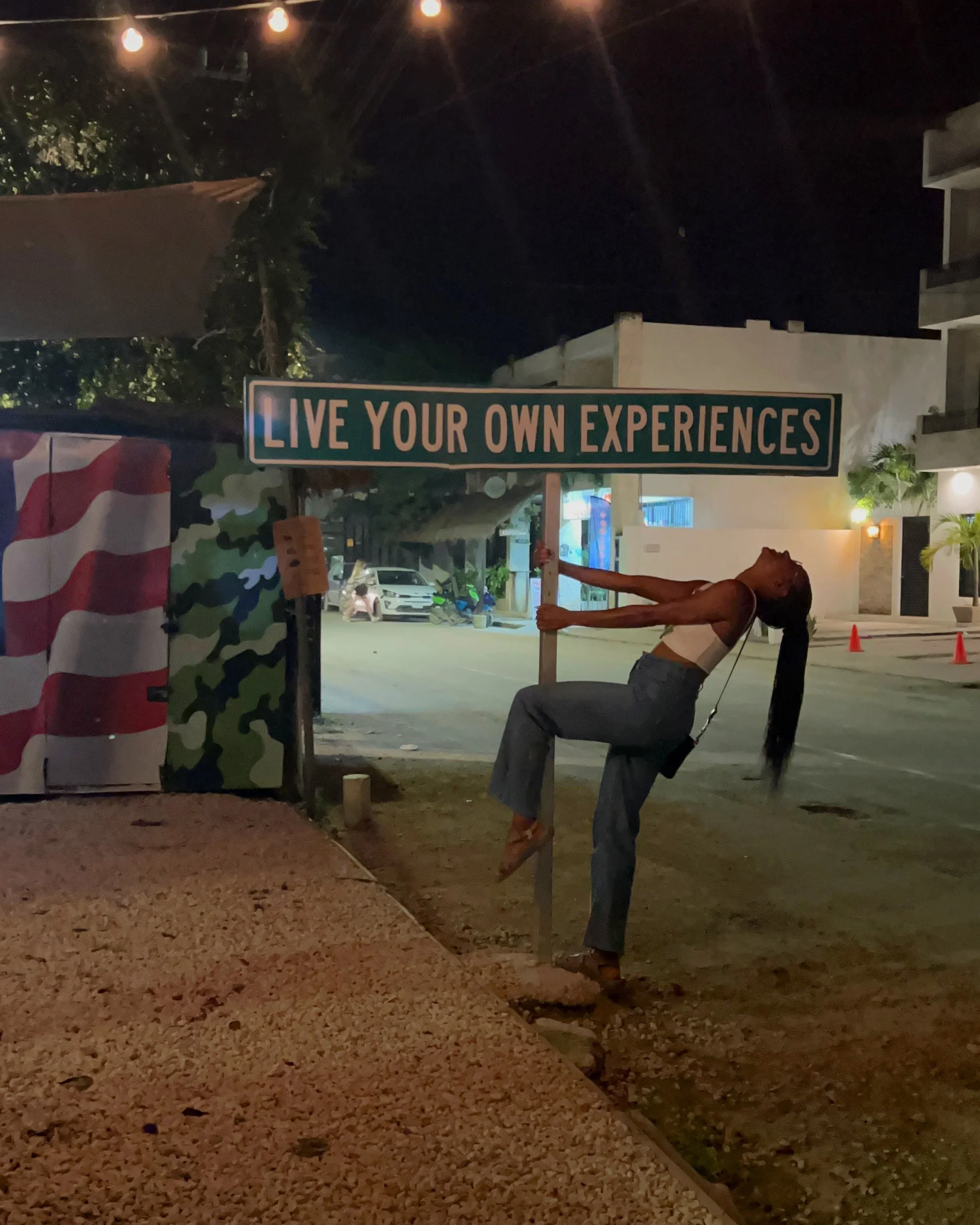 Ashlee roadside under a sign in Tulum, Mexico