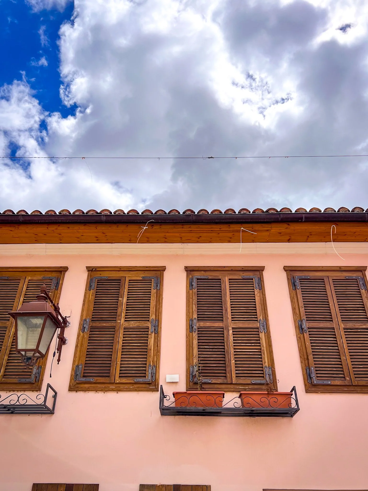 Peach building with wooden shutters and an iron lantern in Vlore Old Town, Albania