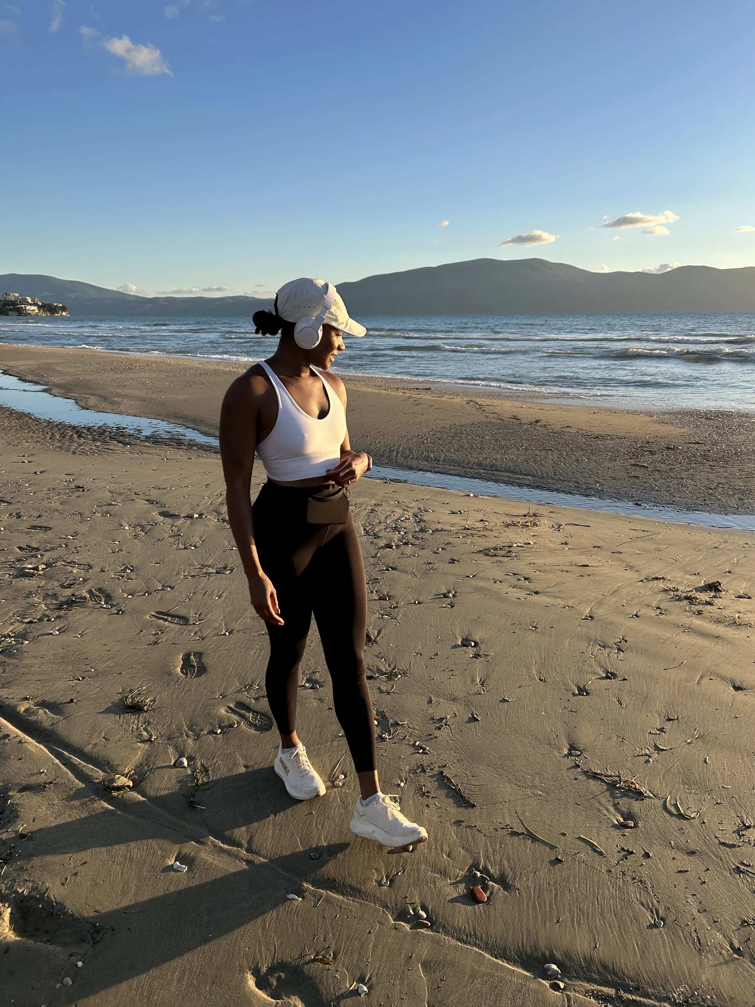 Woman in running gear standing on the beach at sunrise after a morning run, Vlore, Albania