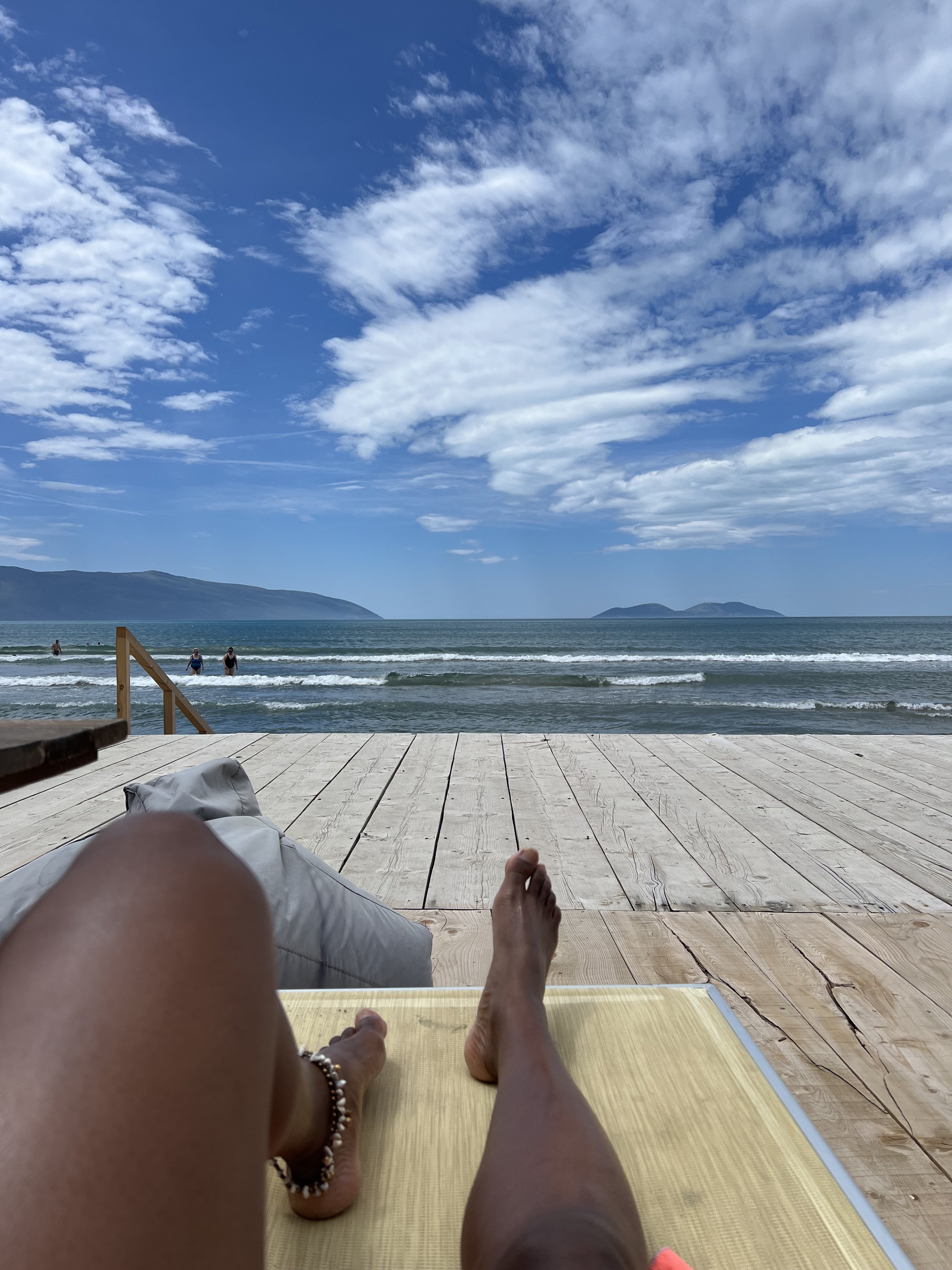 Bare feet stretched out on a wooden deck overlooking the sea, Vlore, Albania