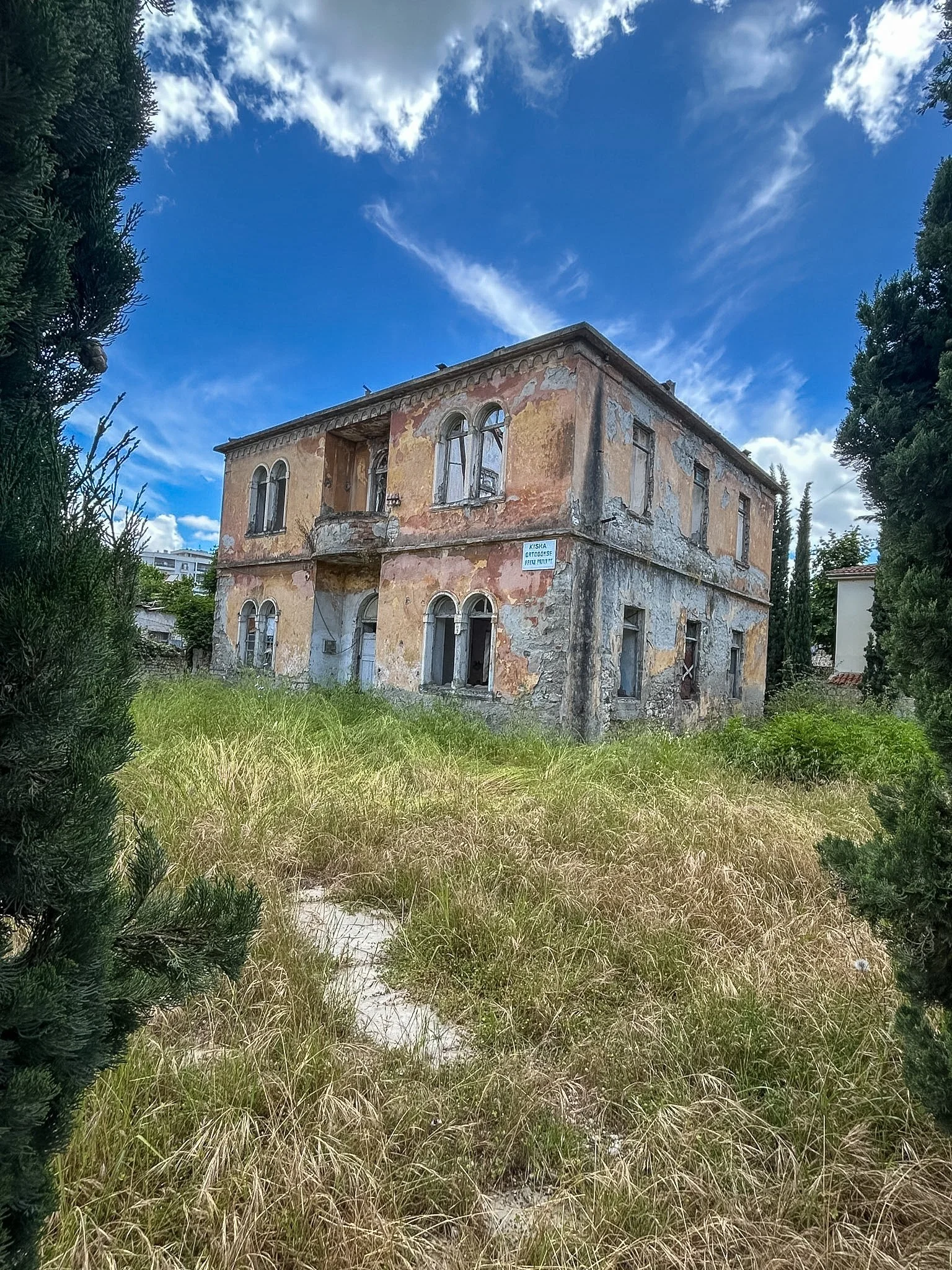 Old weathered villa surrounded by overgrown grass and trees, Vlore, Albania