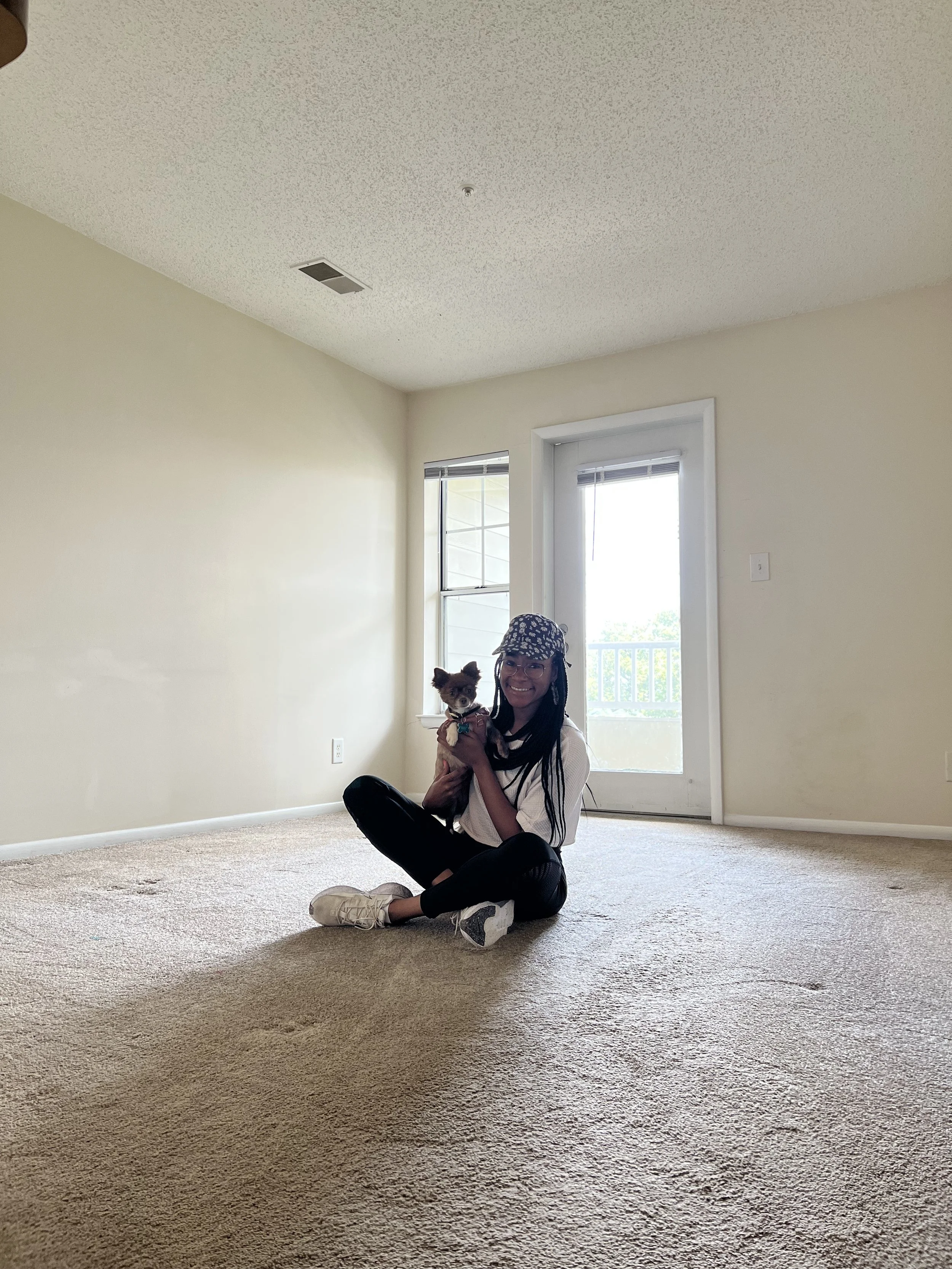 Ashlee sitting in an empty apartment with a small dog before packing up and moving abroad