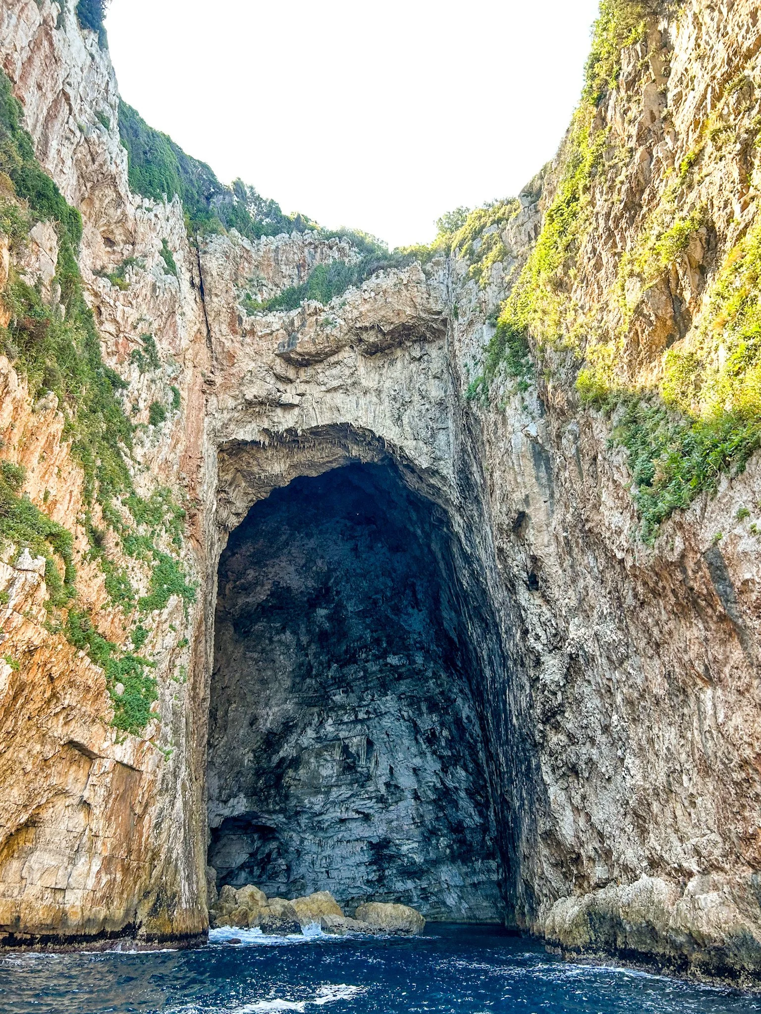 The wide limestone mouth of Haxhi Ali Cave seen from the water, Karaburun Peninsula
